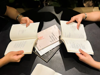 Hands holding open books around a table