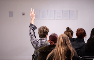 Person raising hand in a classroom setting with audience