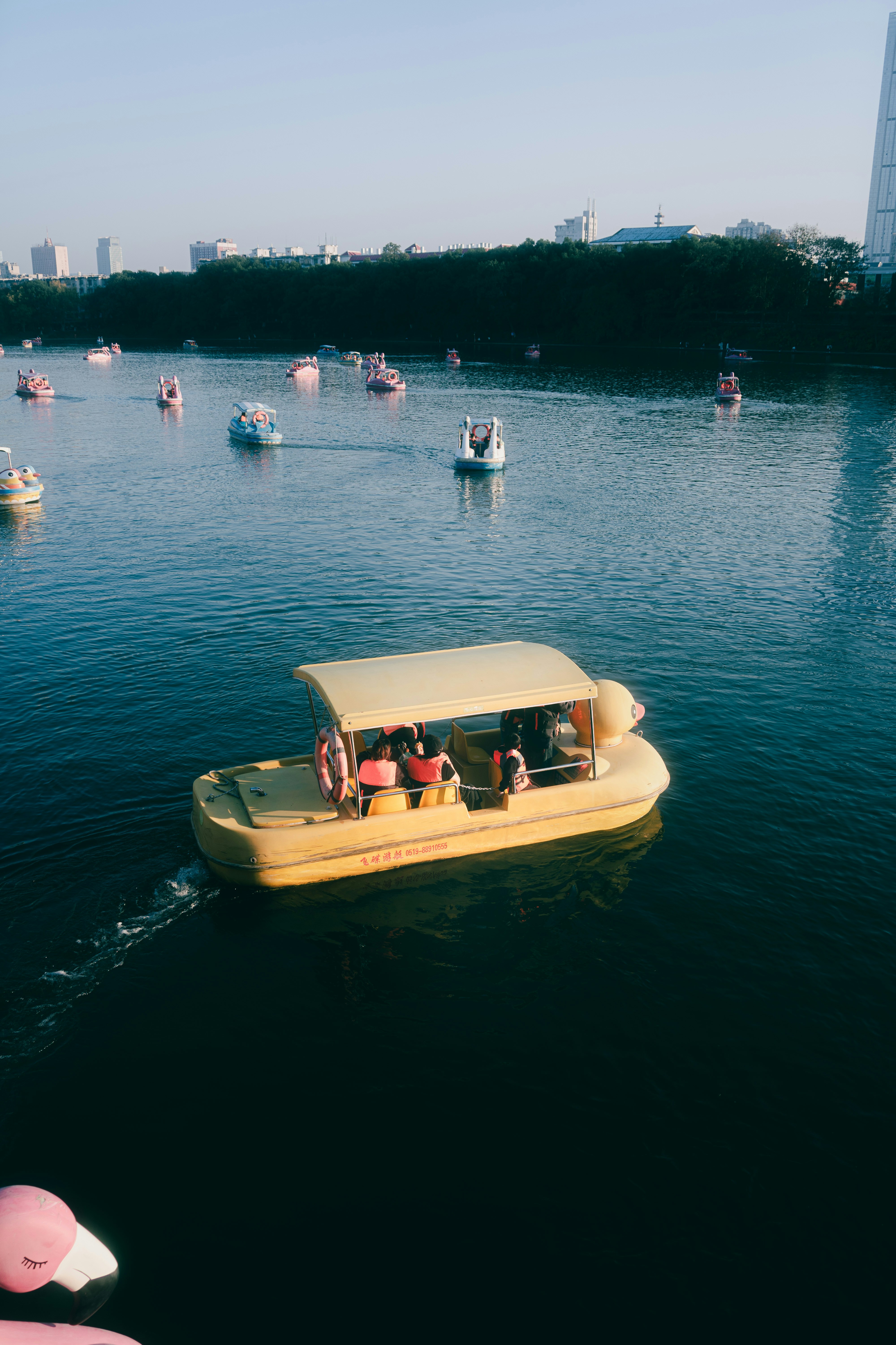 People ride yellow pedal boats on a lake.