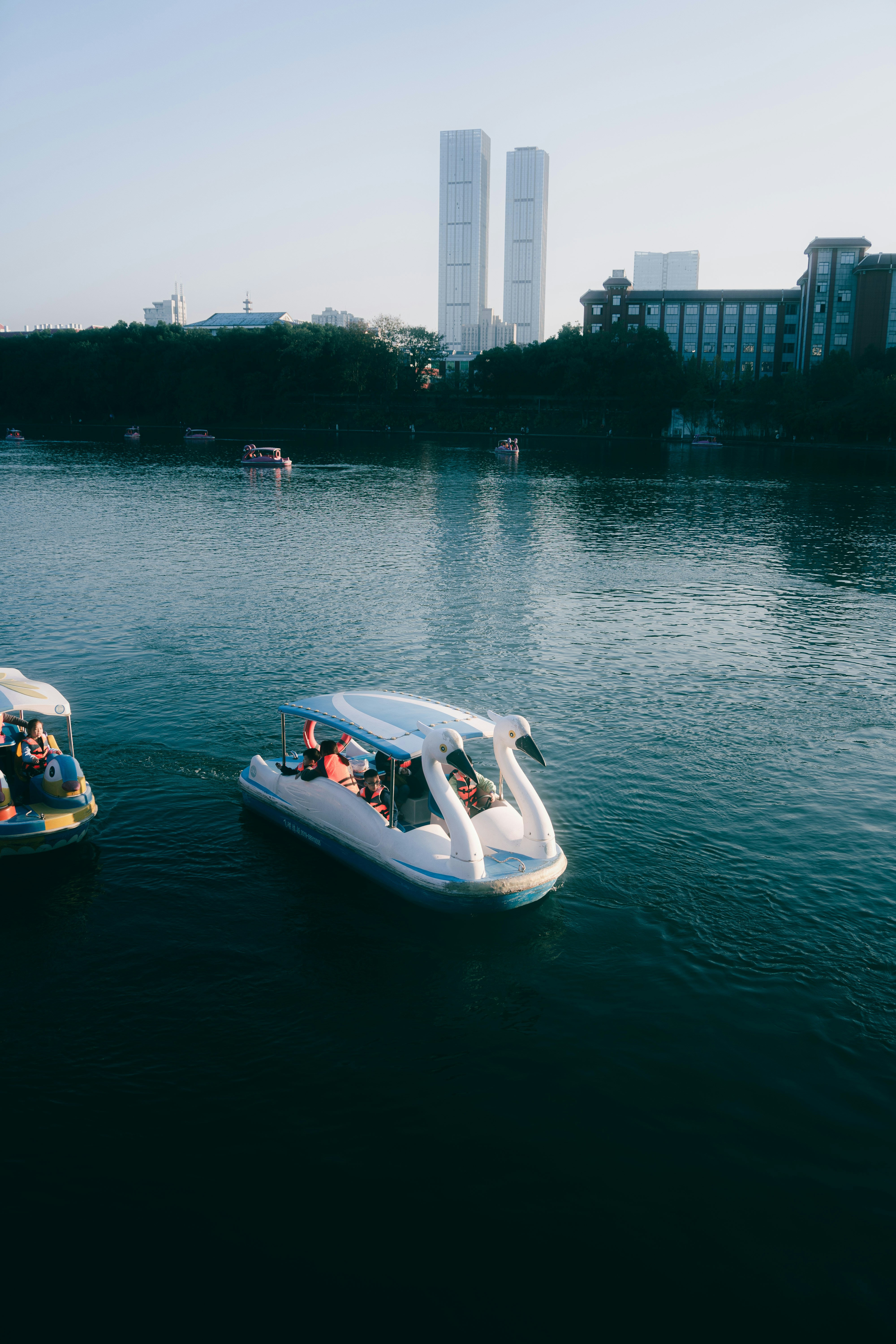People enjoy a swan boat ride on a lake.
