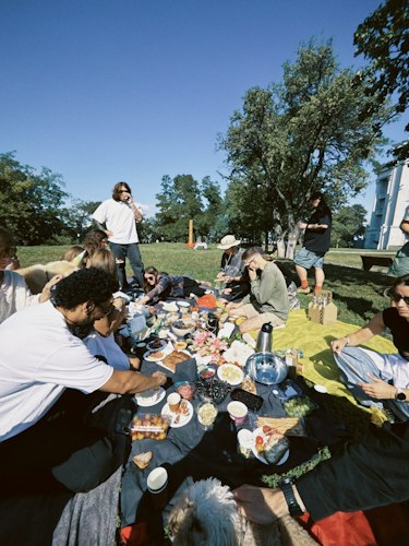 Neighbors chatting and laughing together around a folding table set up on a lawn