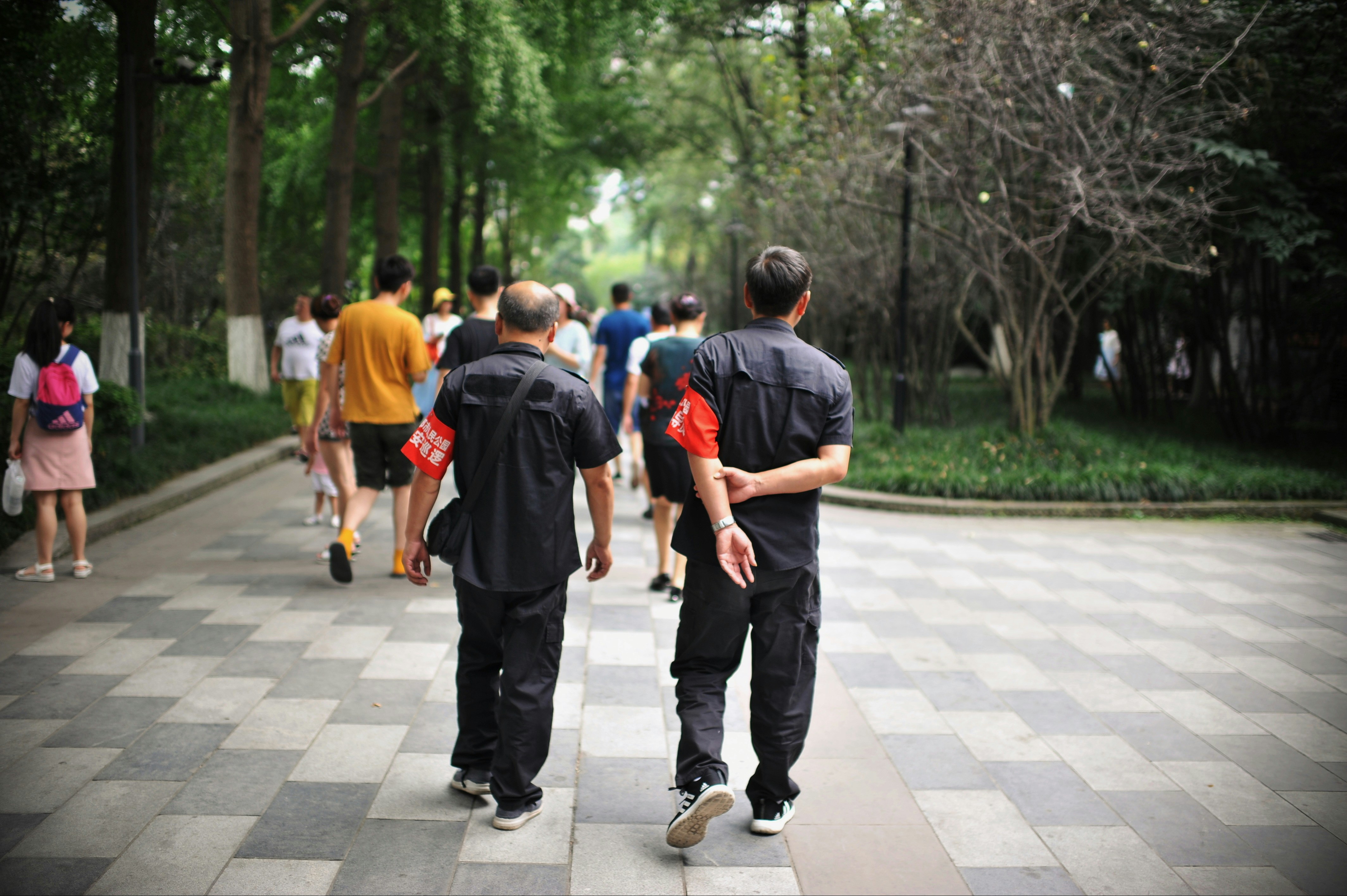 Two men in black shirts walk with a group.