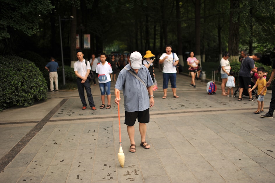 Chengdu Renmin Park - retired man playing with spinning top outdoors