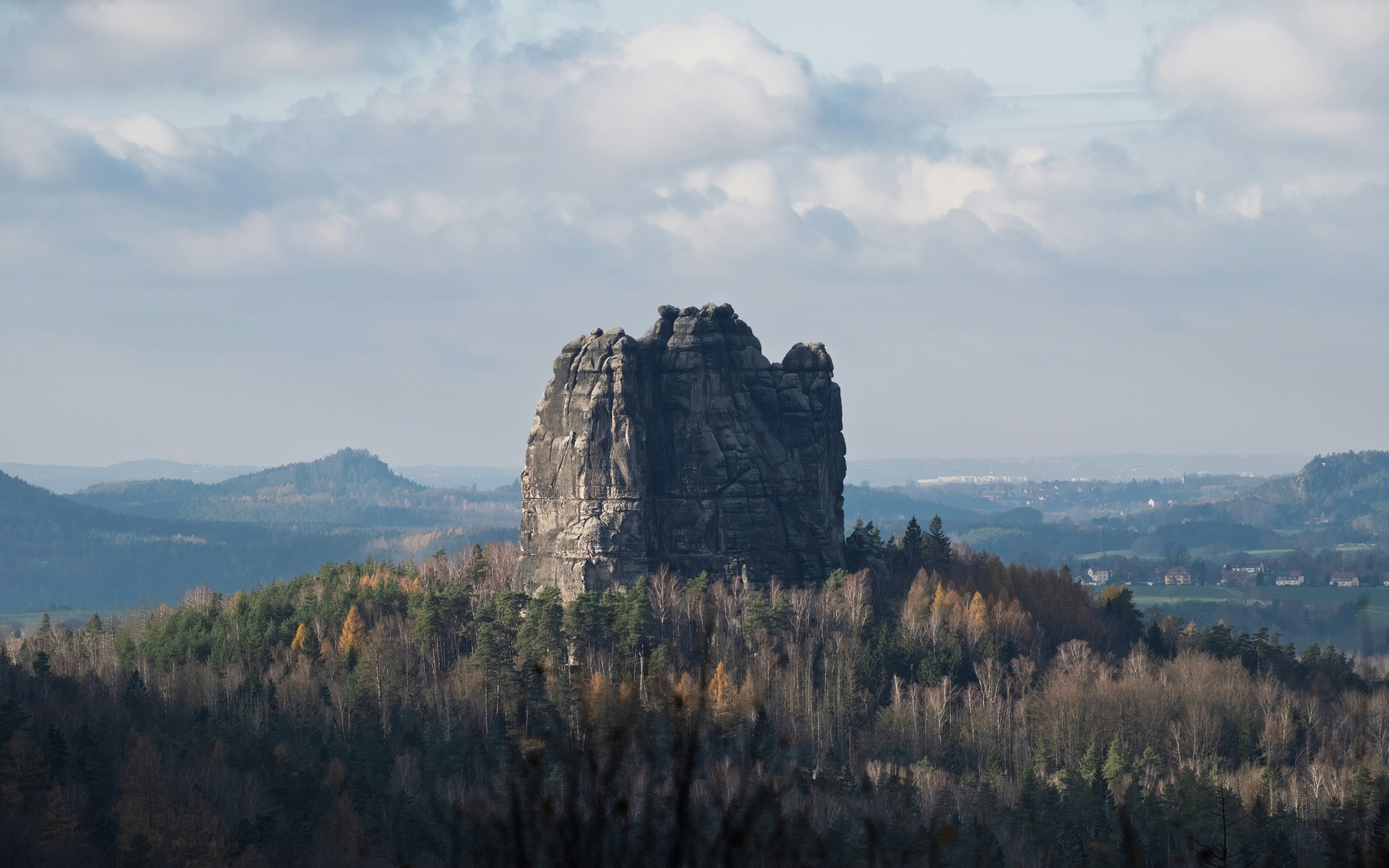 空の下、秋の森に囲まれた岩だらけの峰