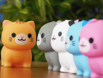 Row of colorful cat figurines with orange one in front