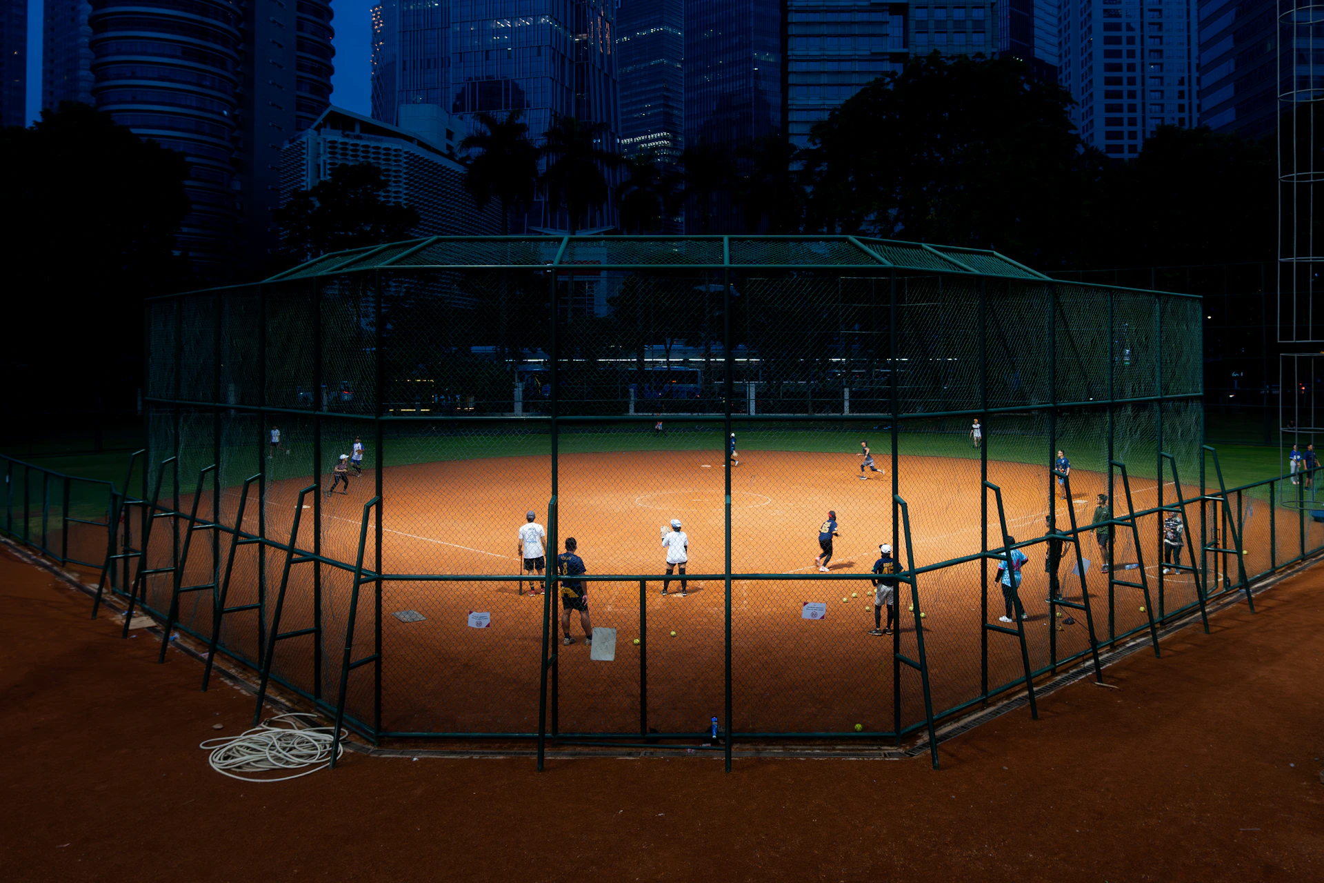 People playing baseball on a lit field at night.