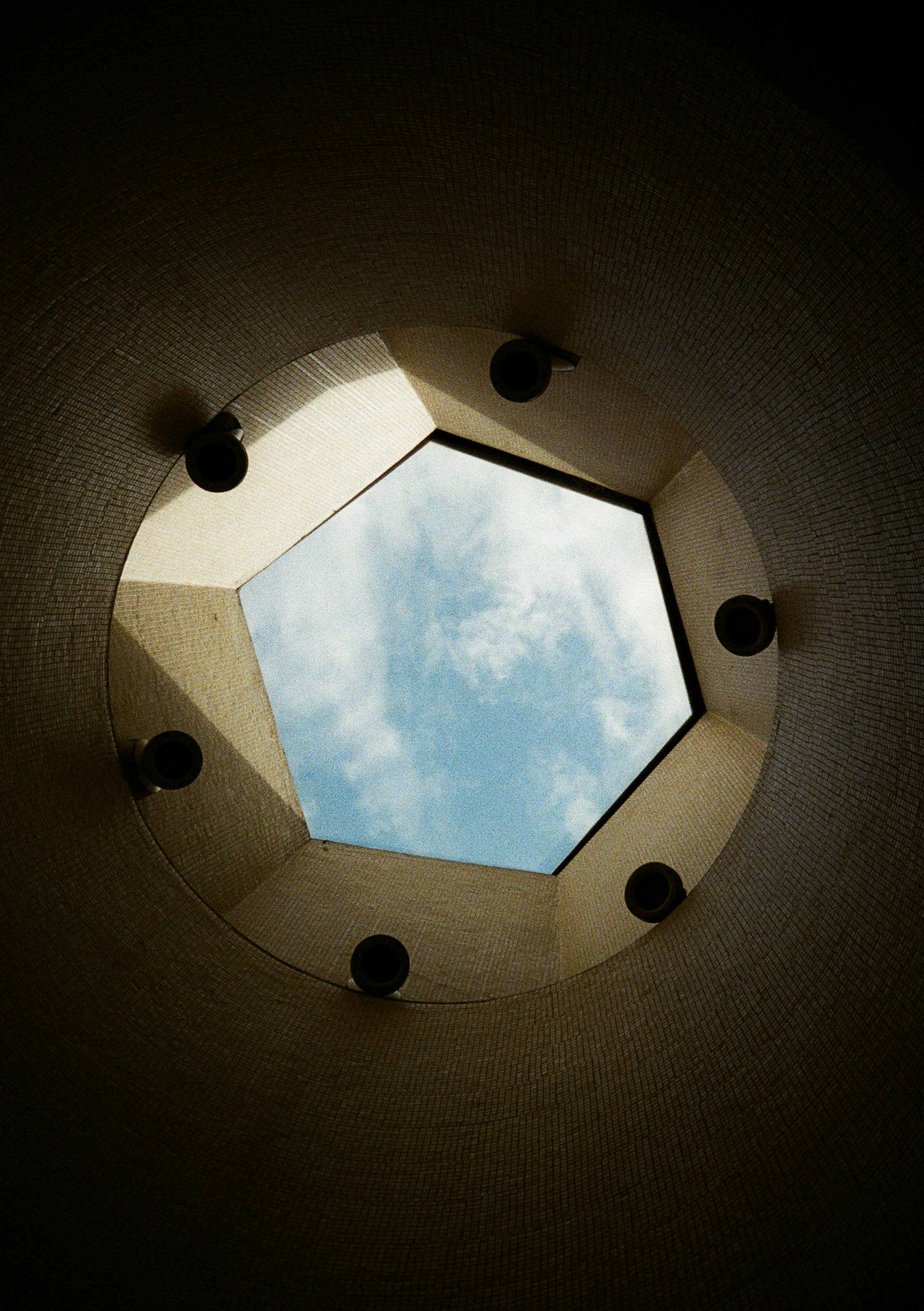 Pentagonal skylight revealing a cloudy blue sky.