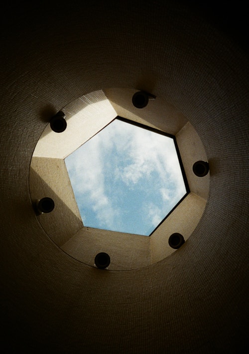 Pentagonal skylight revealing a cloudy blue sky.