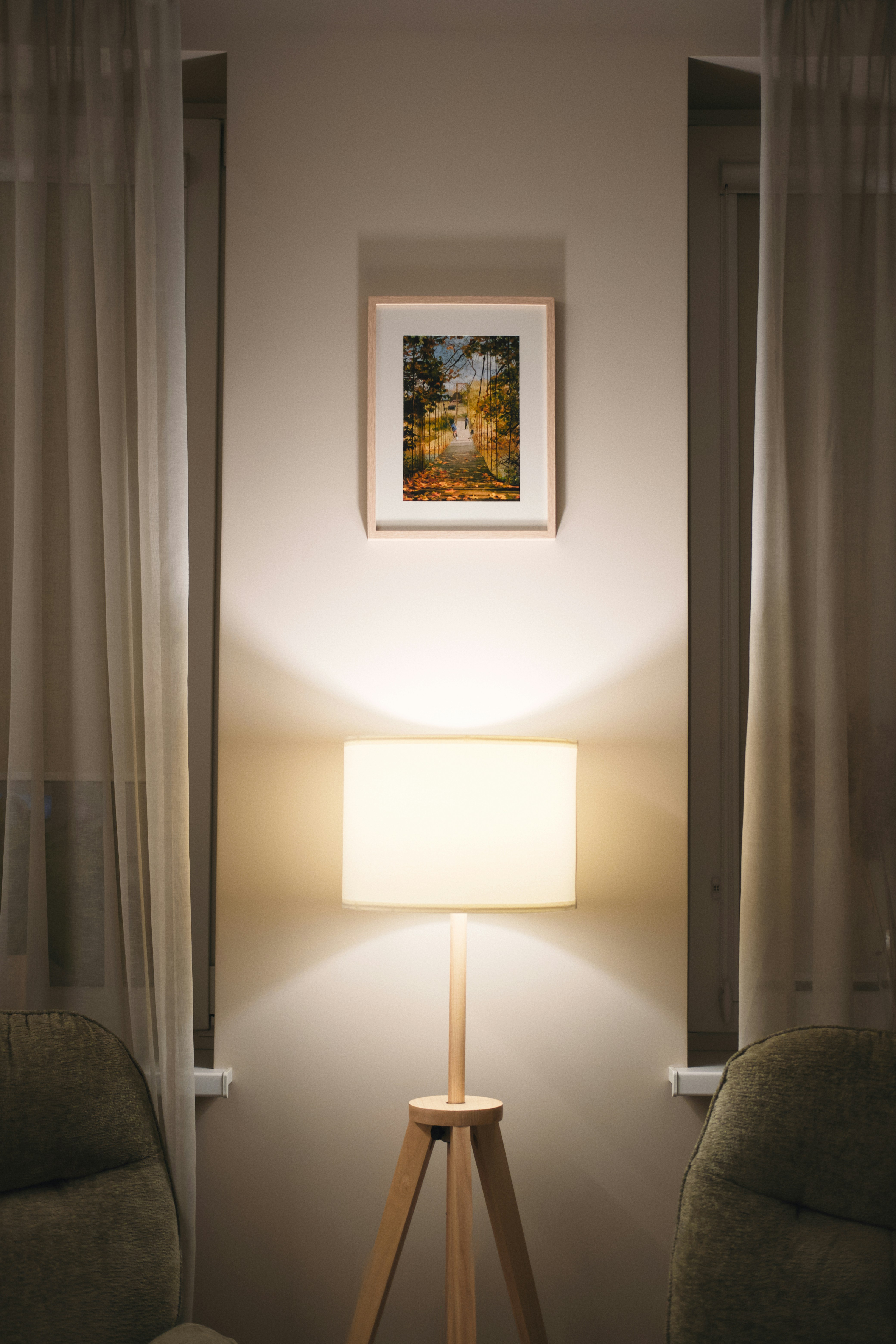 Framed painting of a river scene above a lamp.