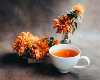 White teacup with orange flowers and rustic background