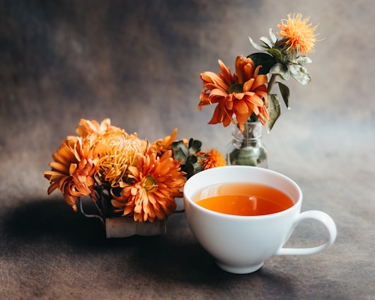 White teacup with orange flowers and rustic background