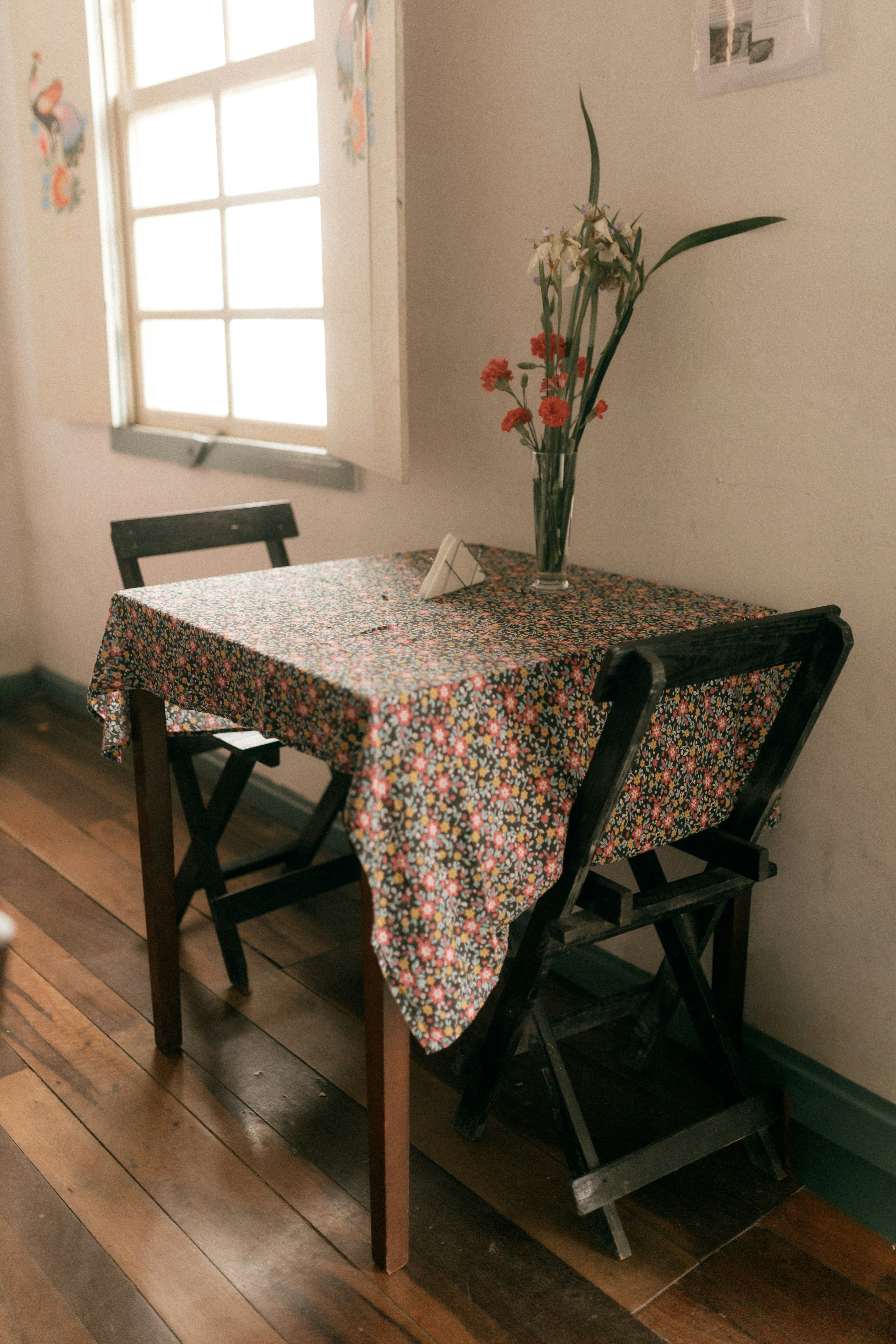 Table with floral cloth and flowers by window