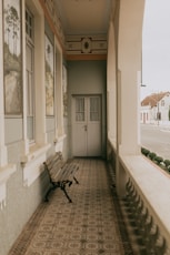 Empty porch with bench and double doors.