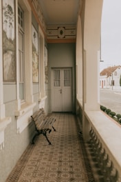 Empty porch with bench and double doors.