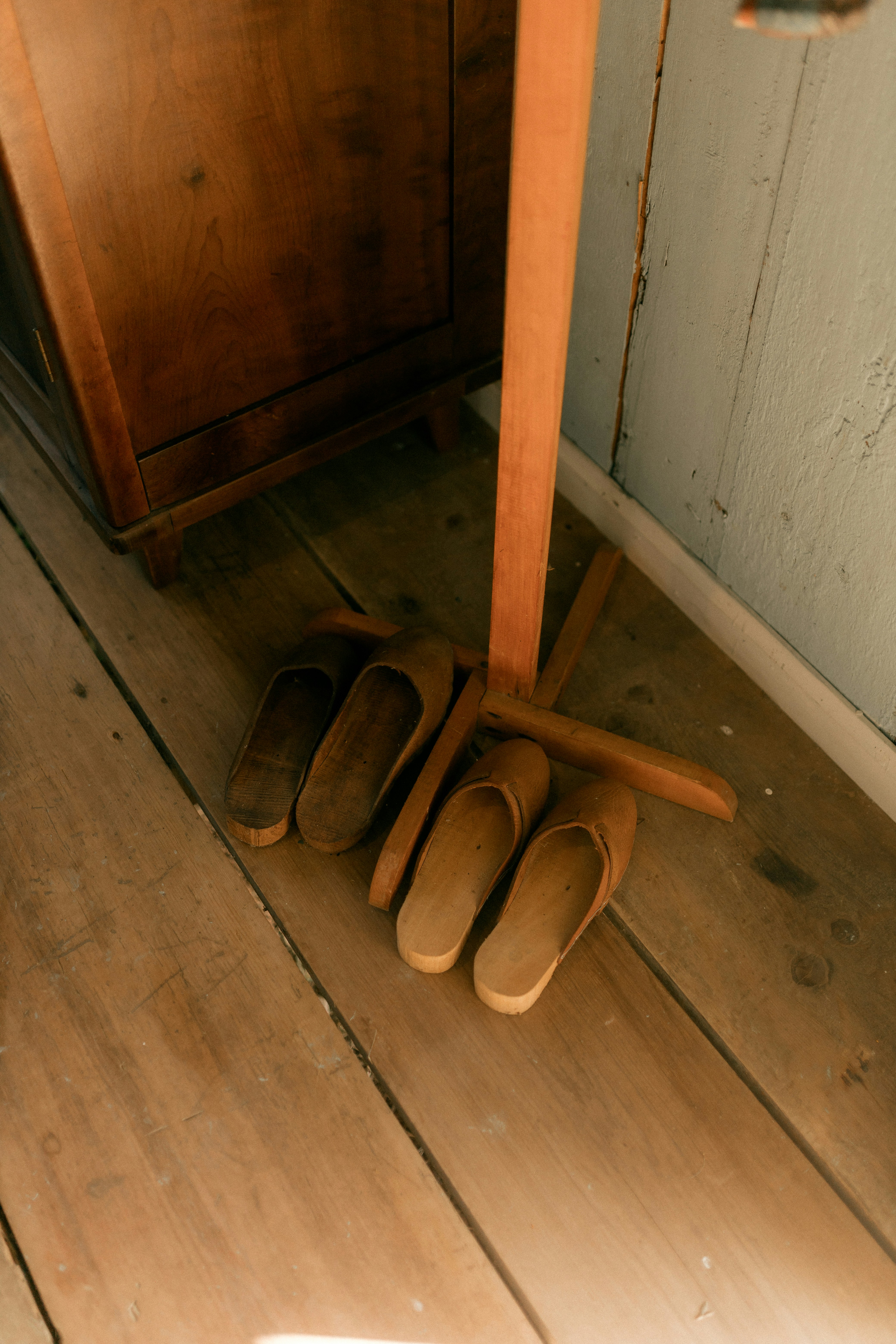 Four pairs of wooden clogs on a wooden floor