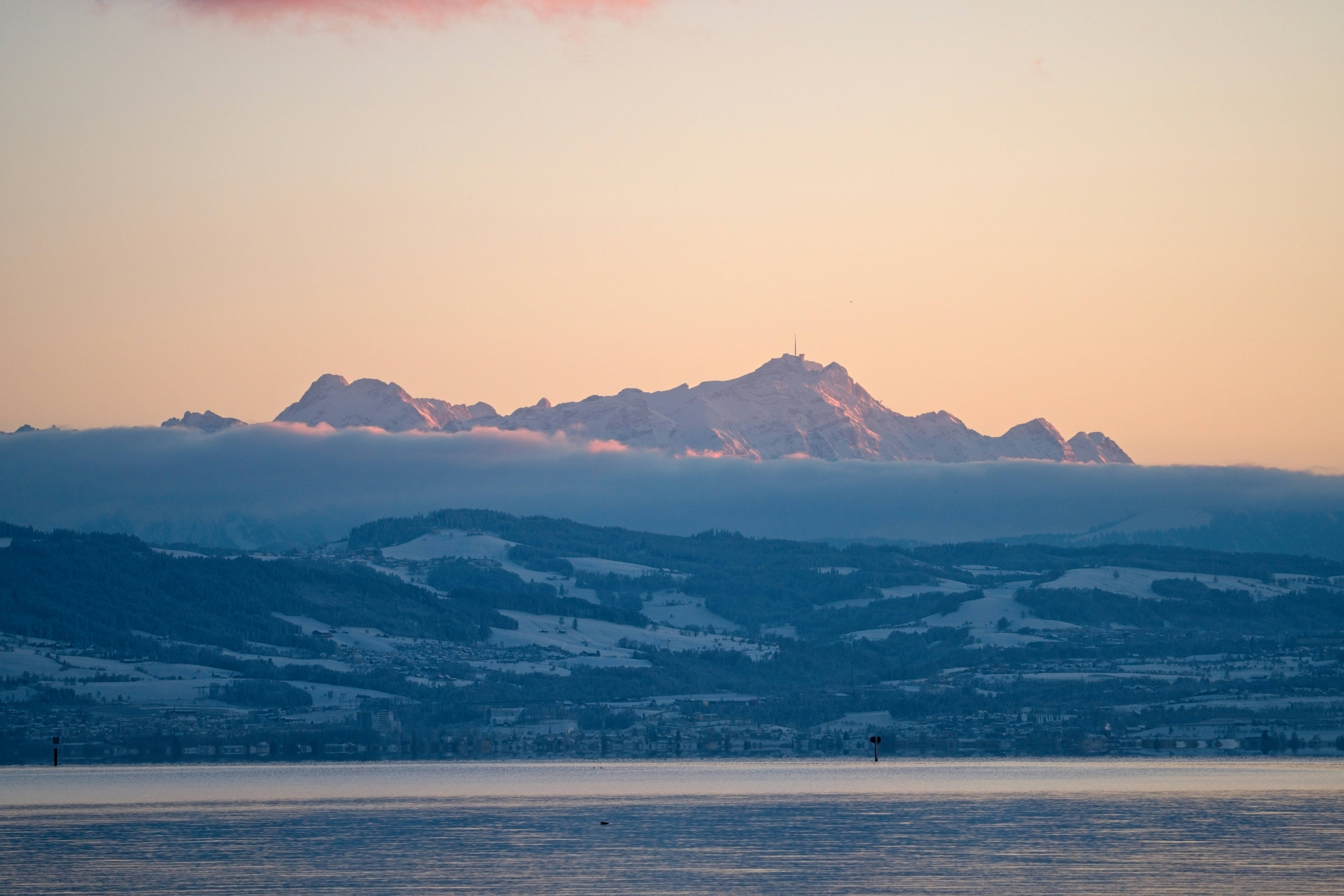 Snow-capped mountains emerging from clouds at sunset in Switzerland