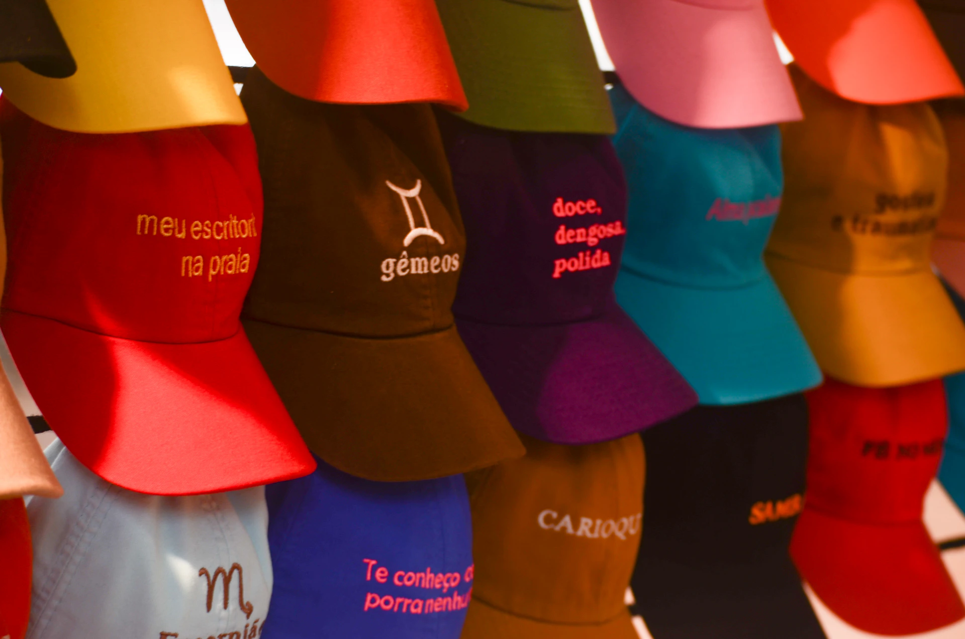 Colorful caps with embroidered text and symbols displayed
