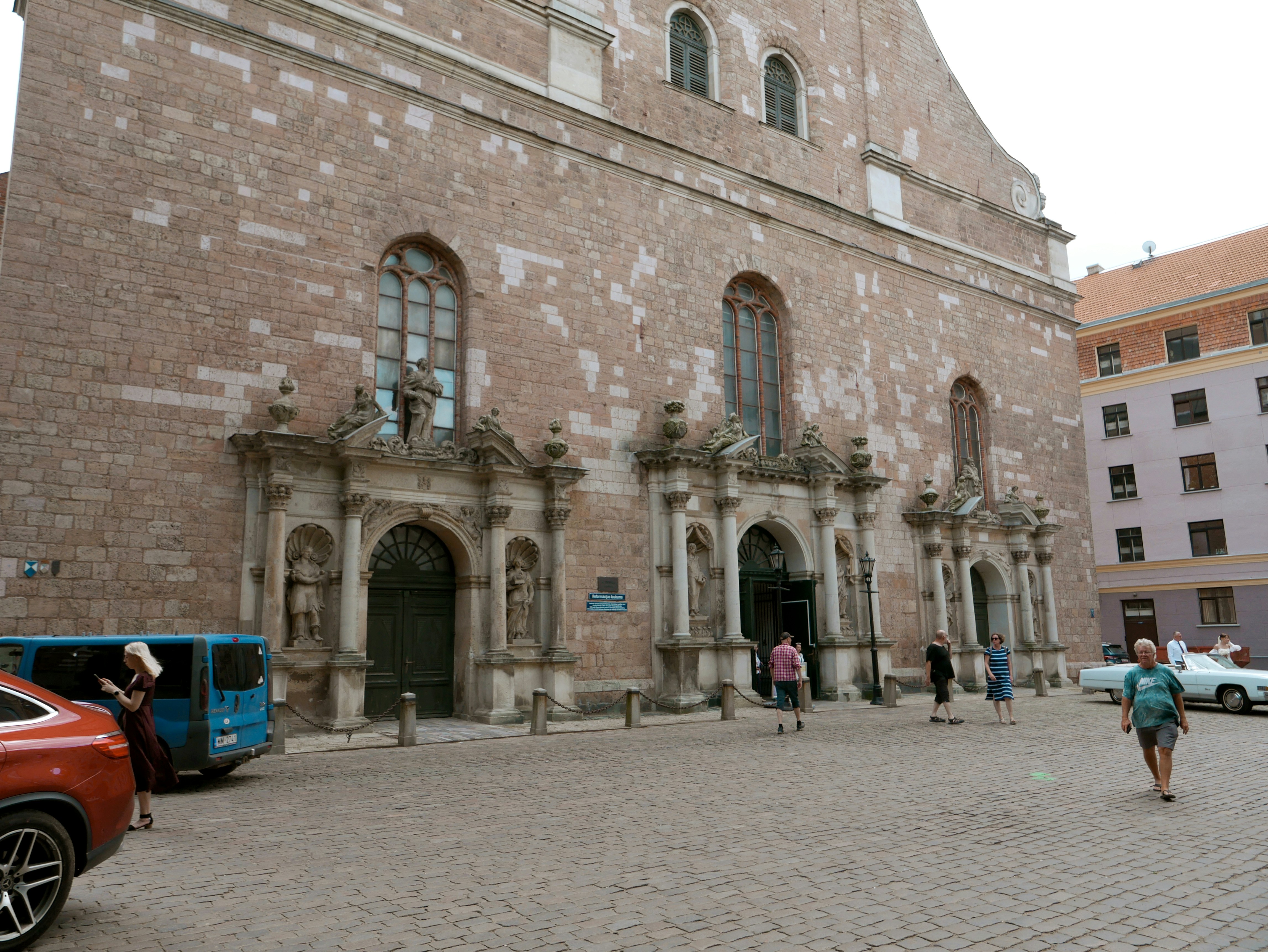 People walk in front of a large stone building entrance.