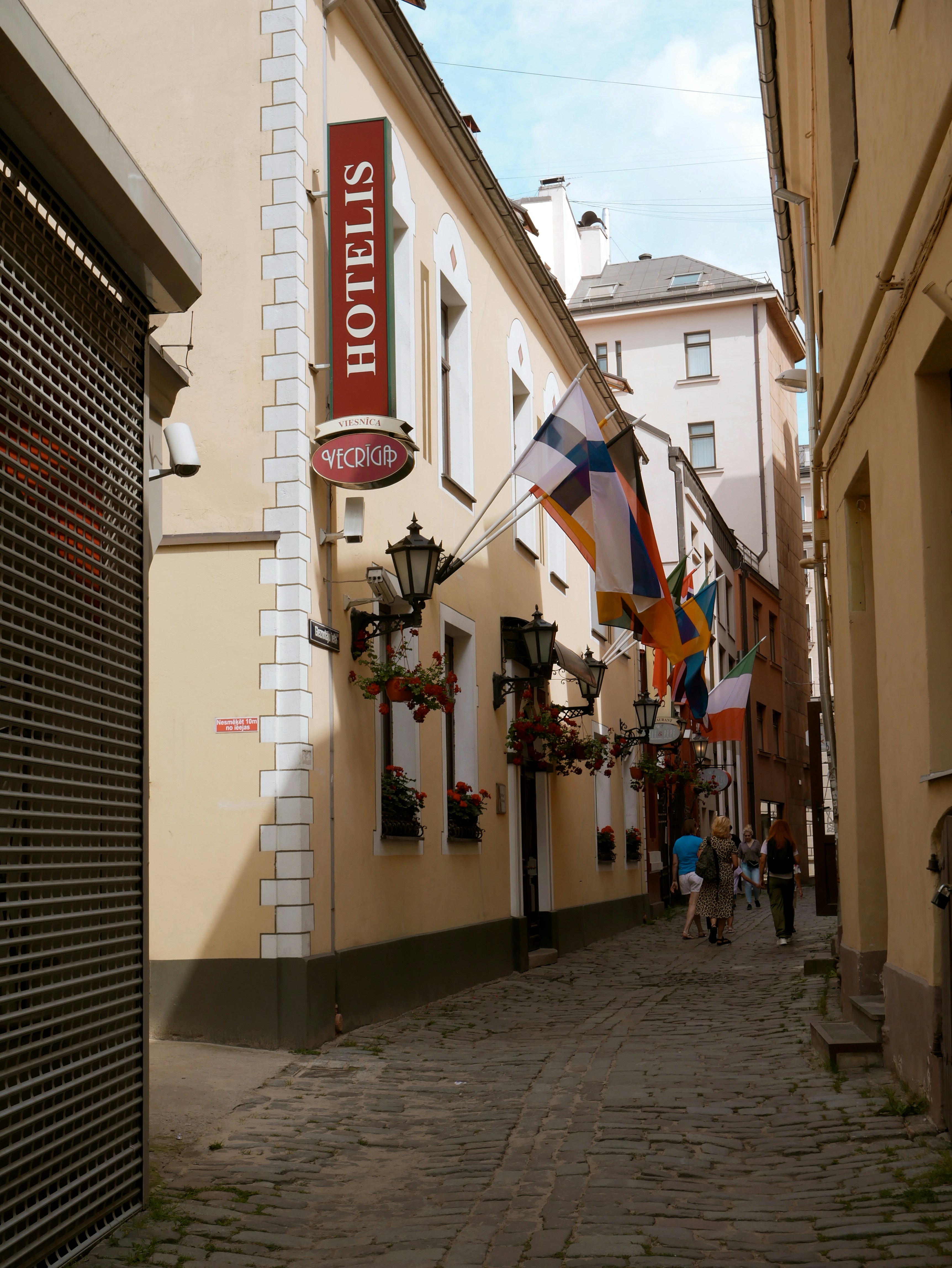 Narrow cobblestone street with flags and hotel sign