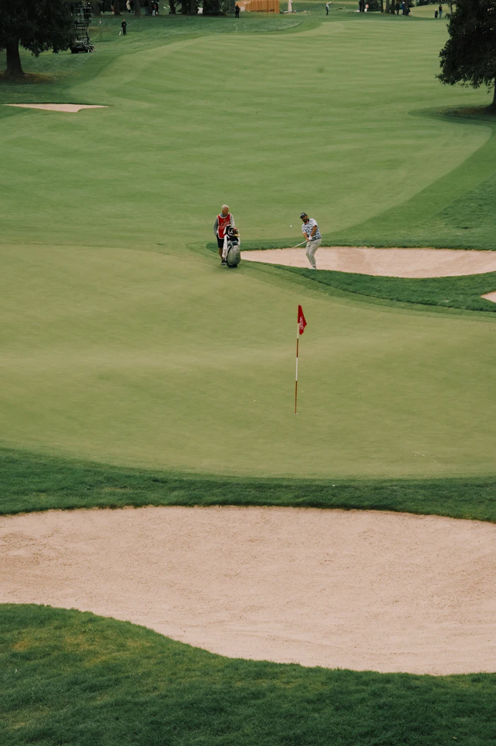Golfers on a putting green beside sand traps