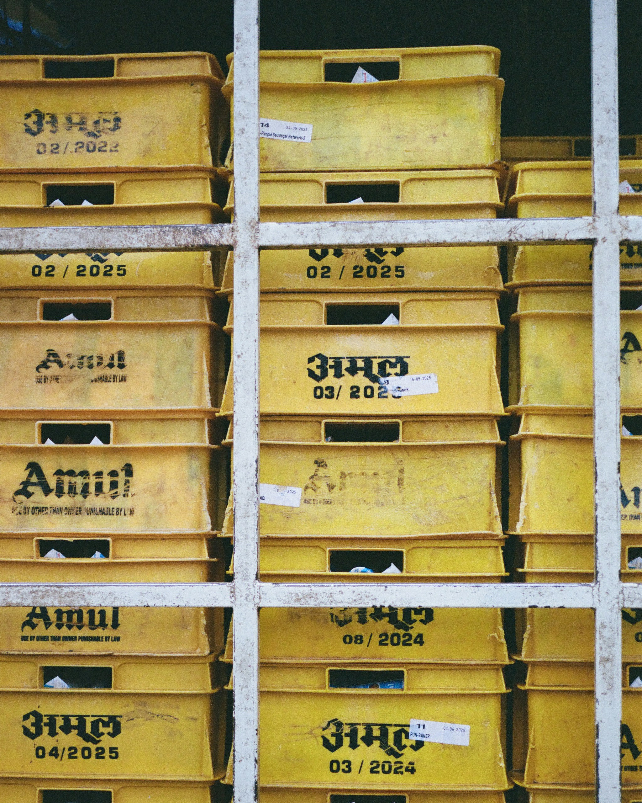 Stacks of yellow amul crates with dates.