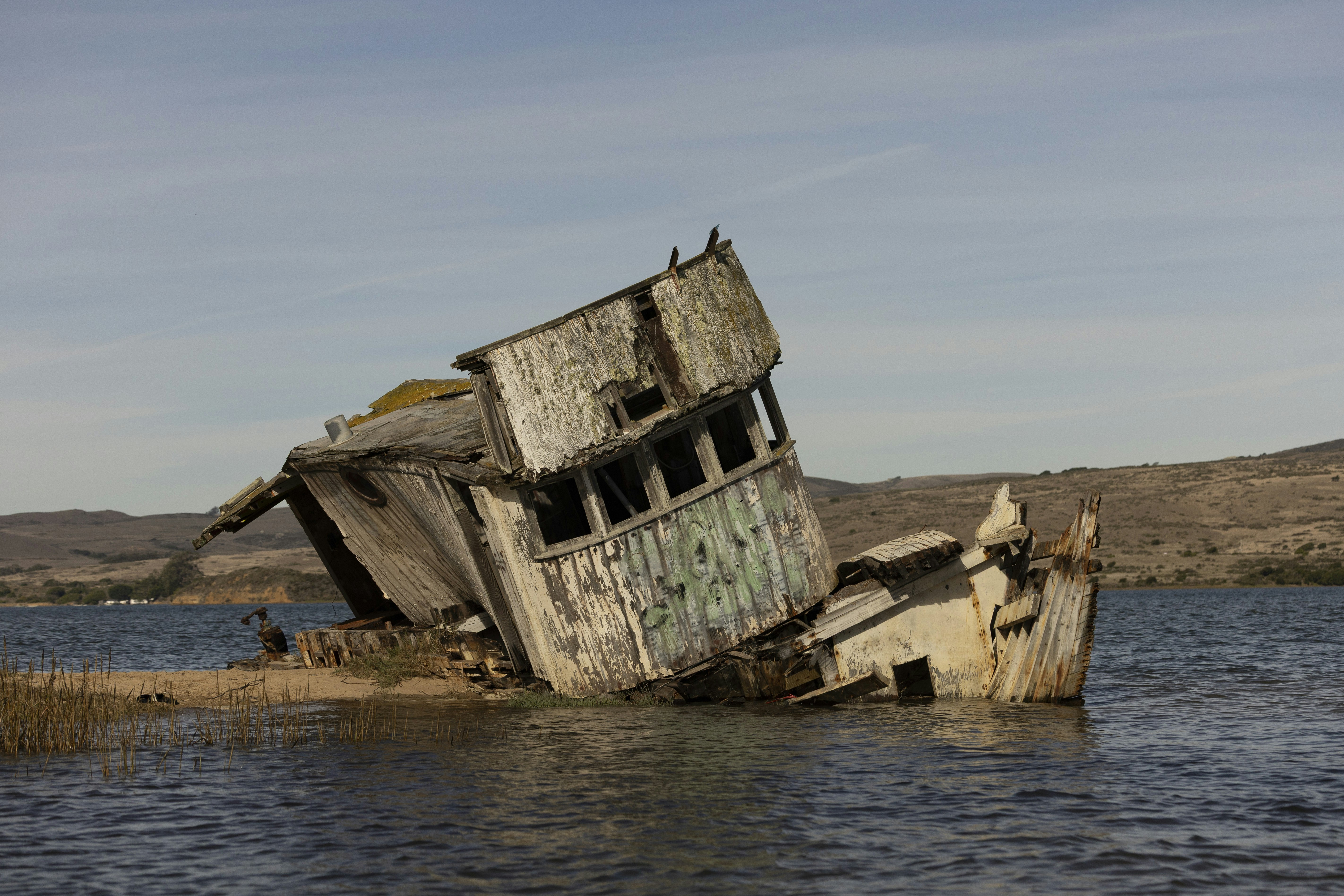 Ein gesunkenes hölzernes Schiffswrack auf einem ruhigen, blauen Meer.