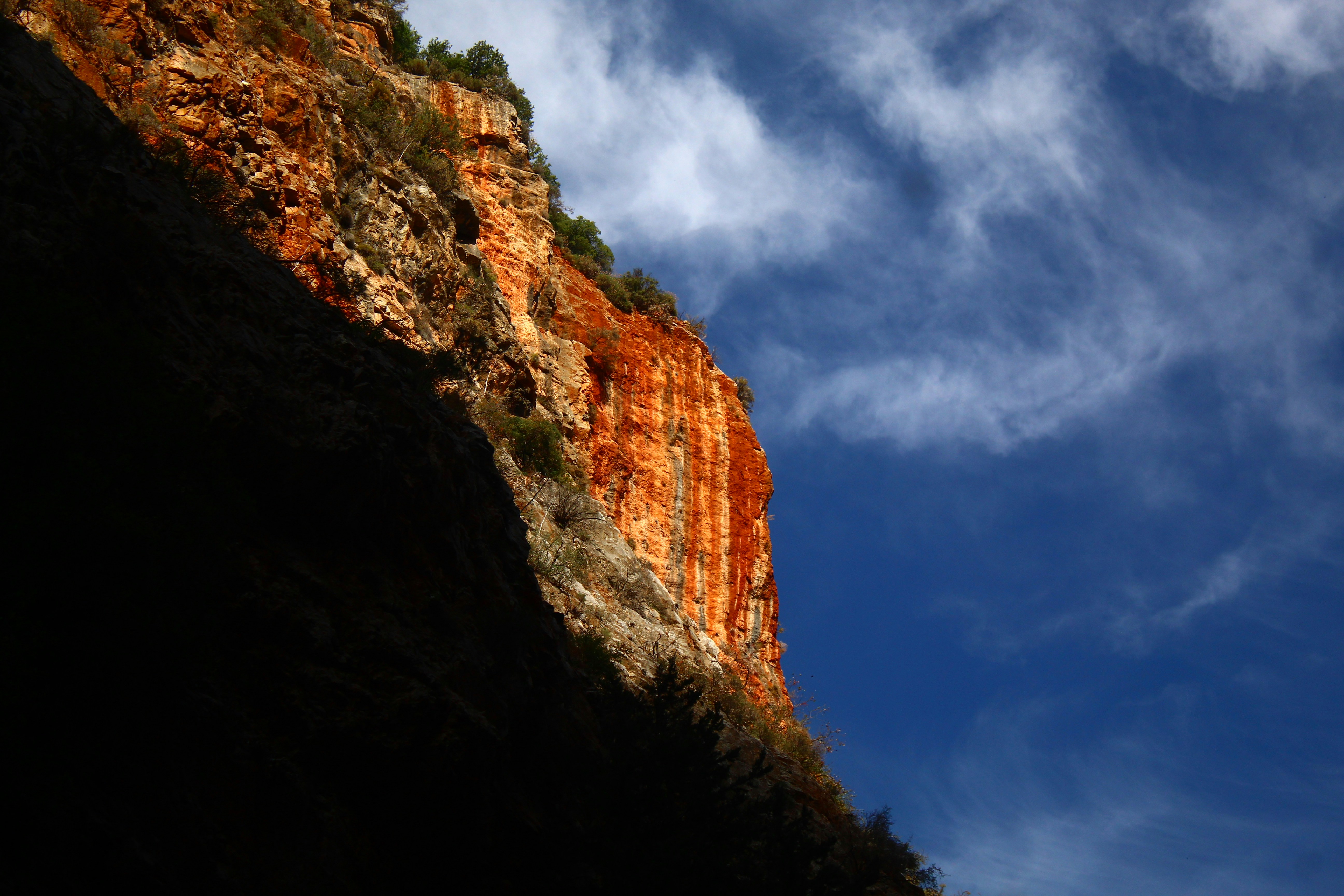 Dramatic red rock cliff face against a blue sky.