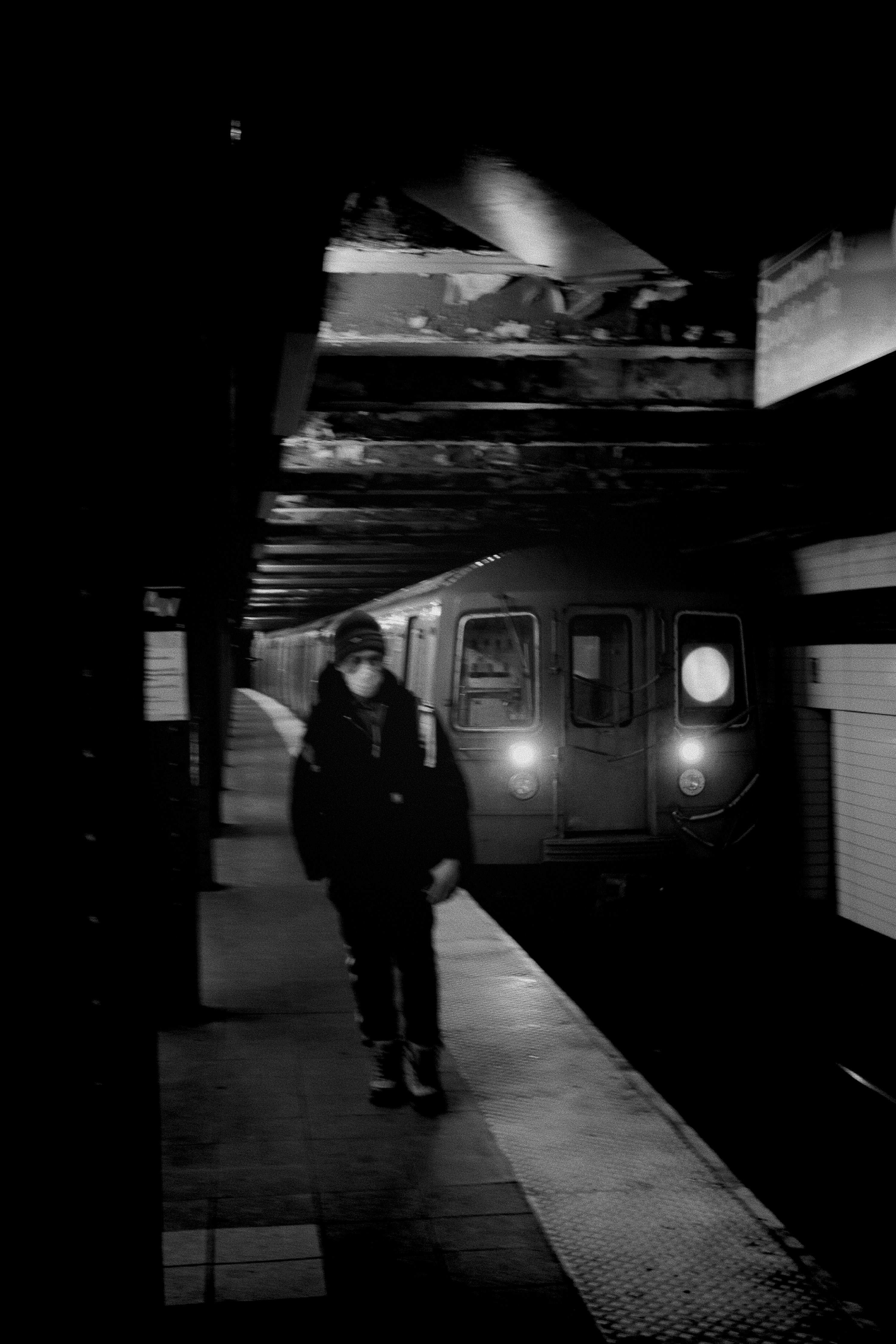 A solitary person walks on a subway platform at night.