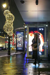 Woman waiting at a bus stop with advertisements