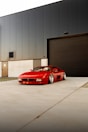 Red sports car parked outside industrial building