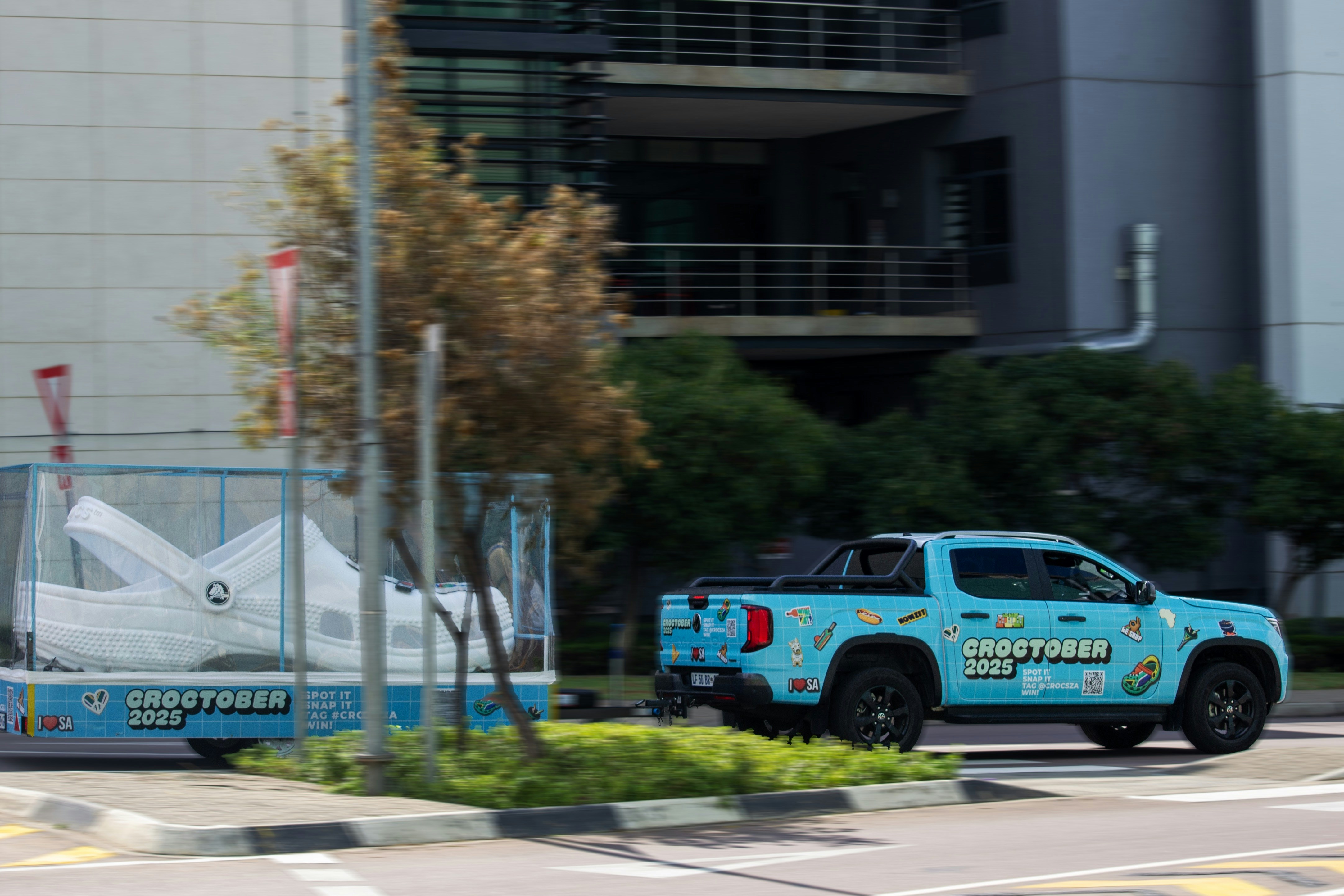 Blue truck towing a large white shoe on a trailer