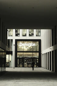 Man walks towards deloitte building entrance.