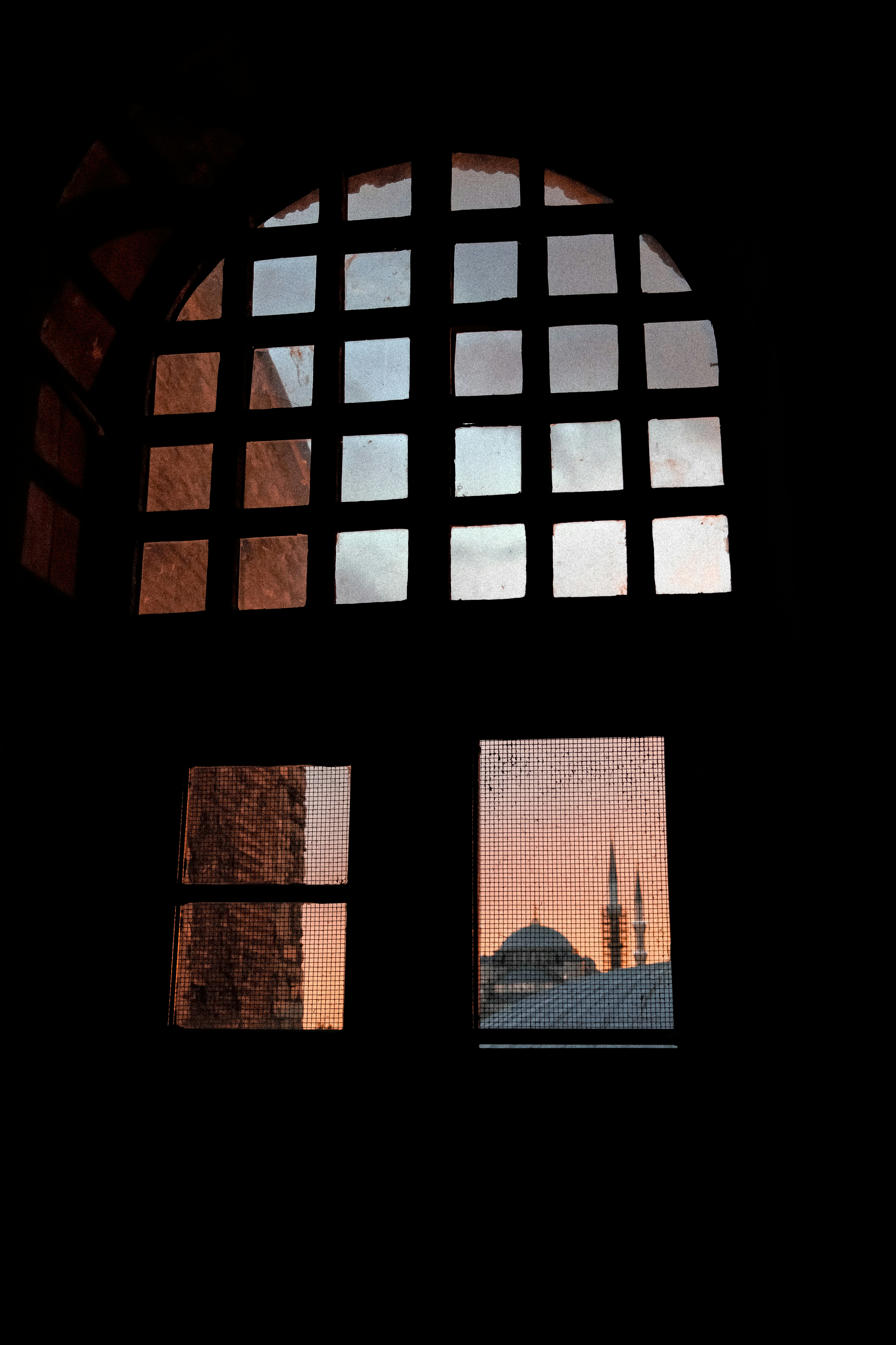View of mosque through arched window at sunset