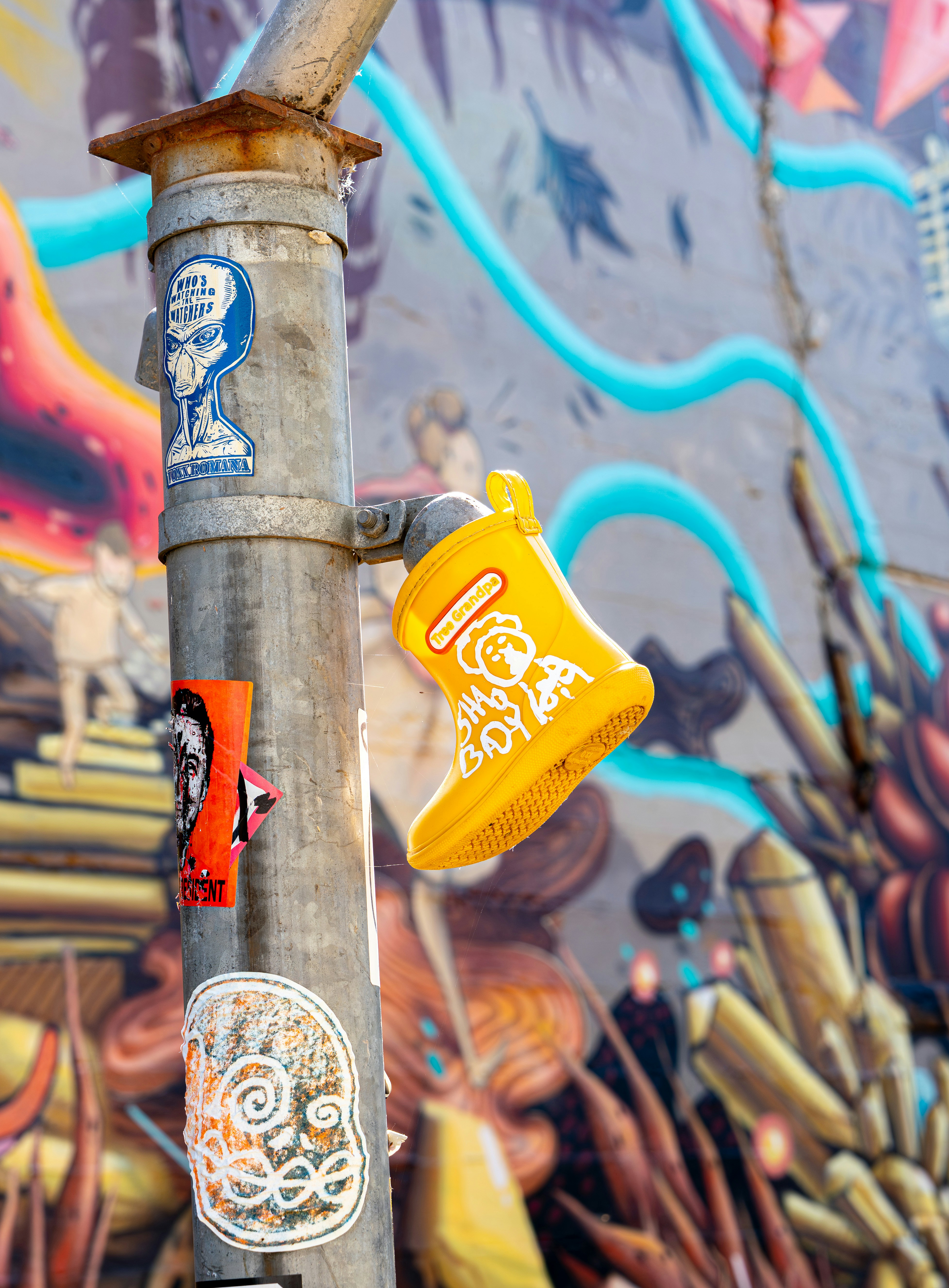 Bota amarela presa a um poste coberto de grafite.