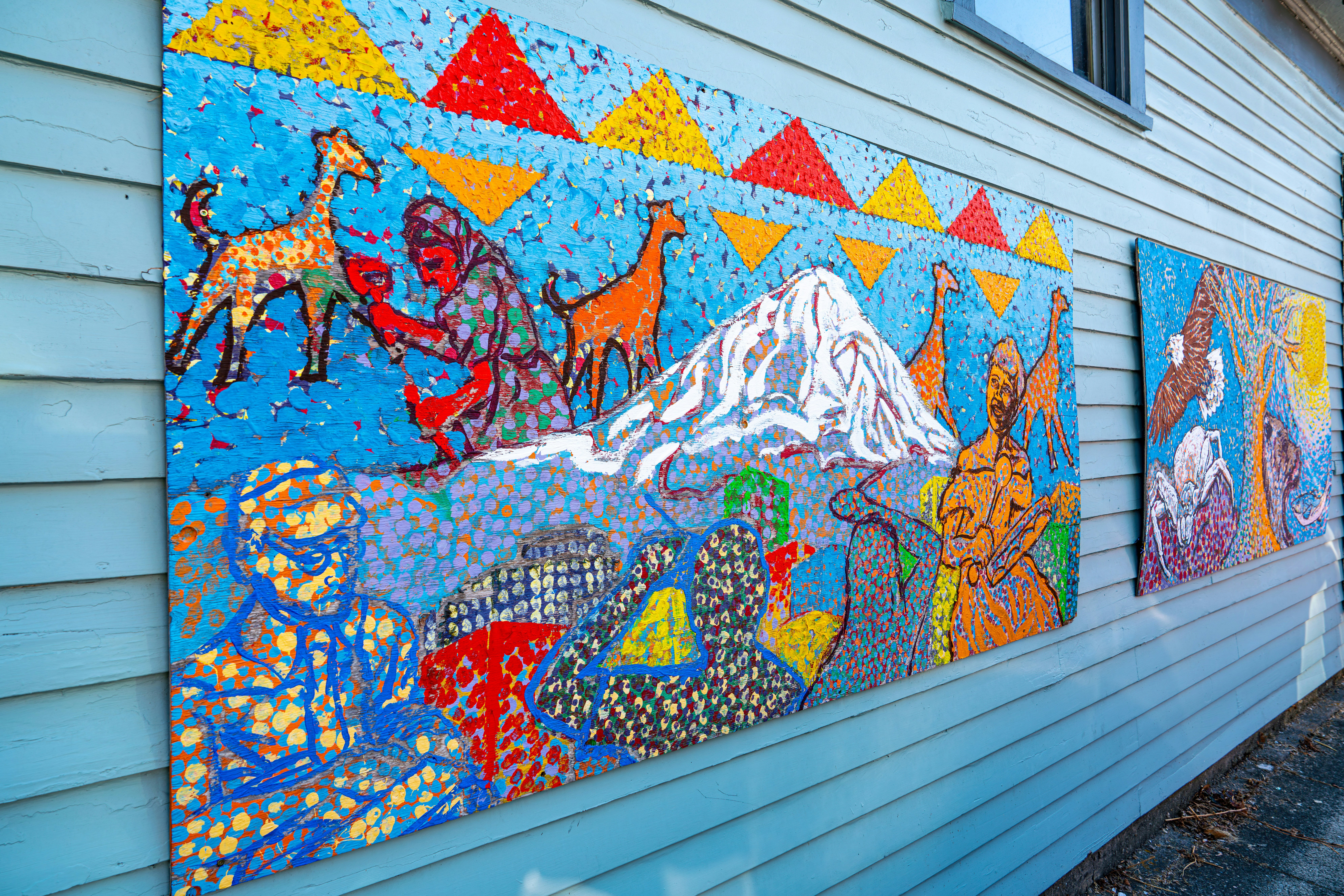 Mural colorido em mosaico retratando pessoas e animais