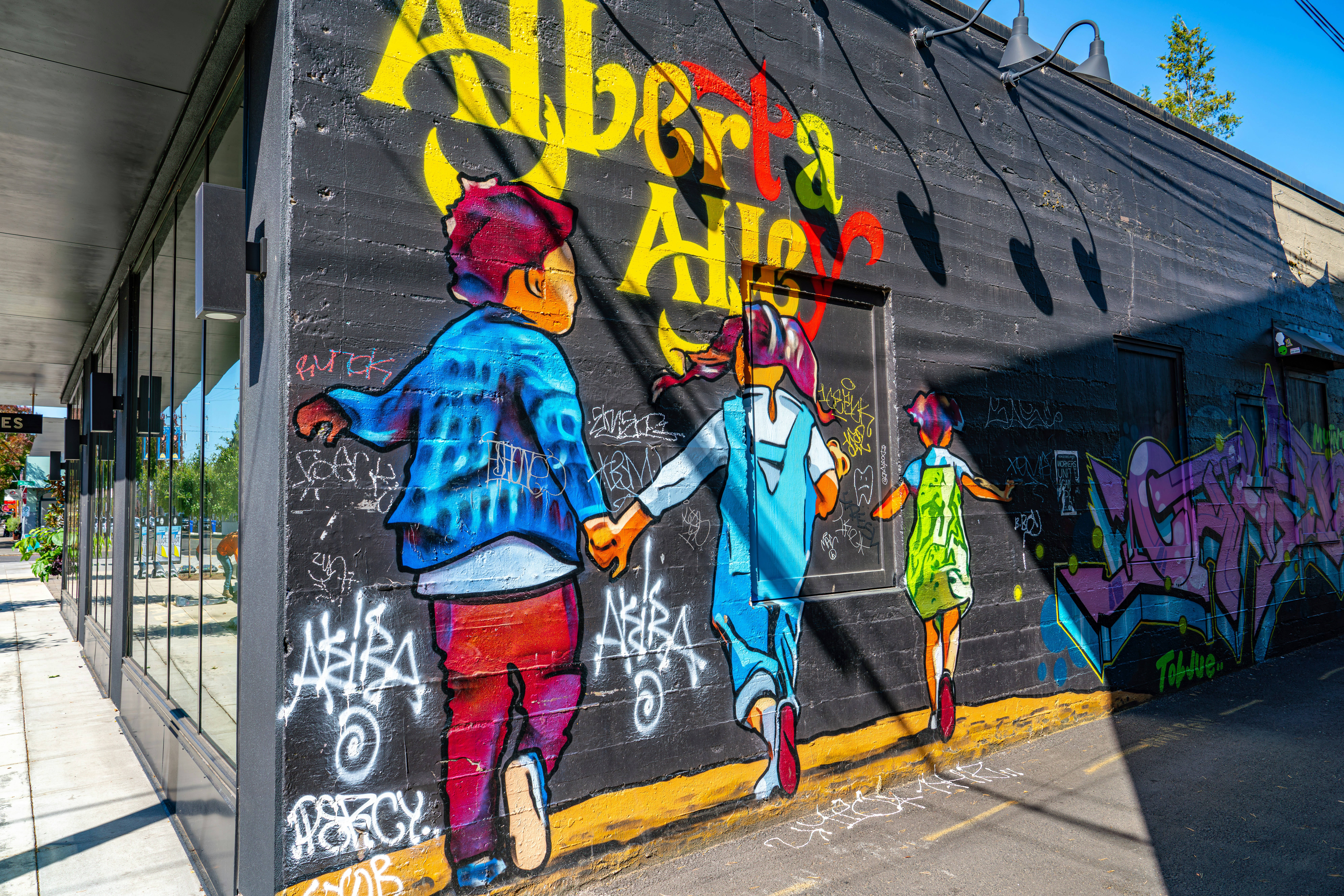 Children walk past a mural with graffiti art