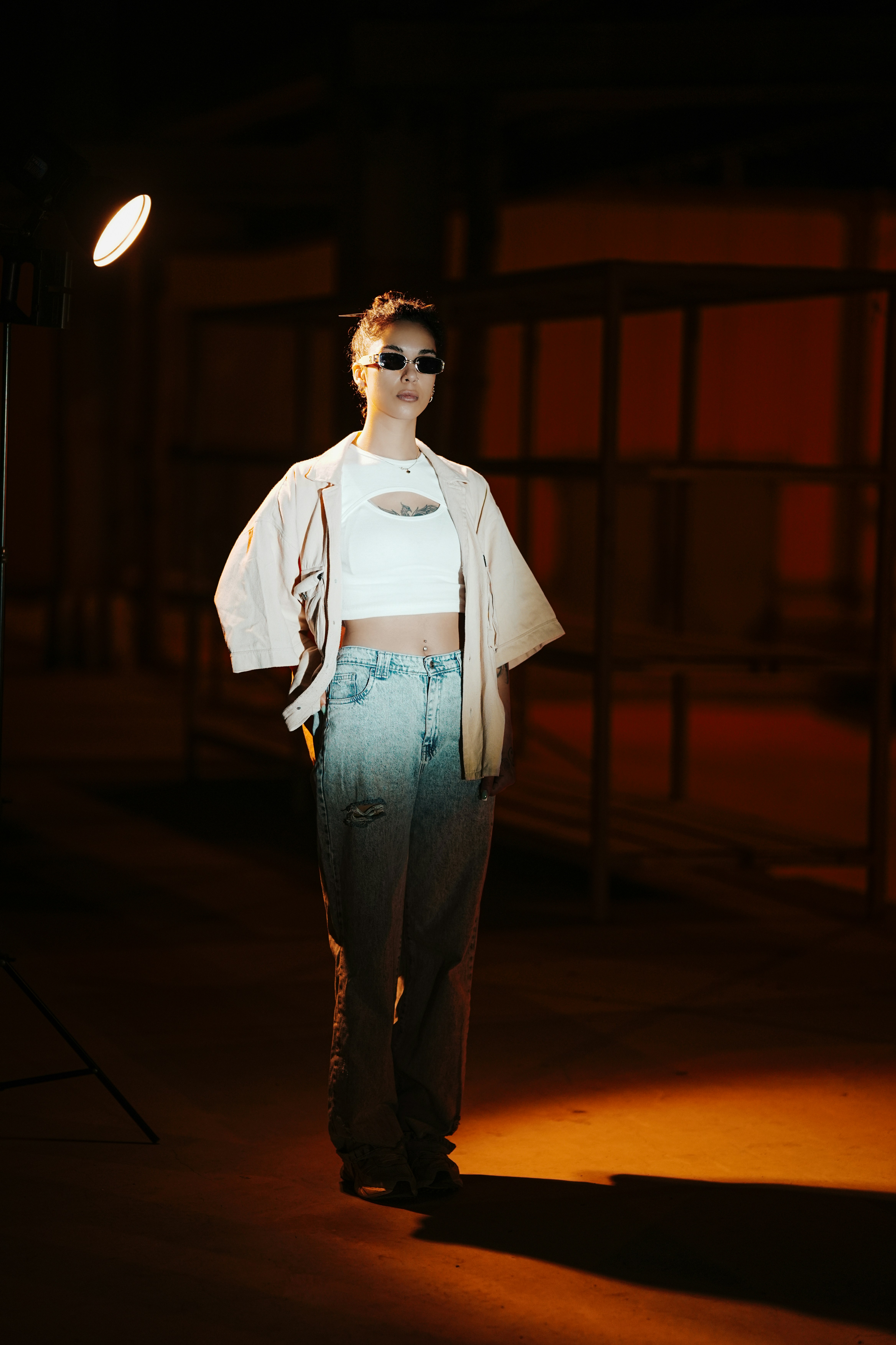 Mujer con gafas de sol y crop top posando en interiores.