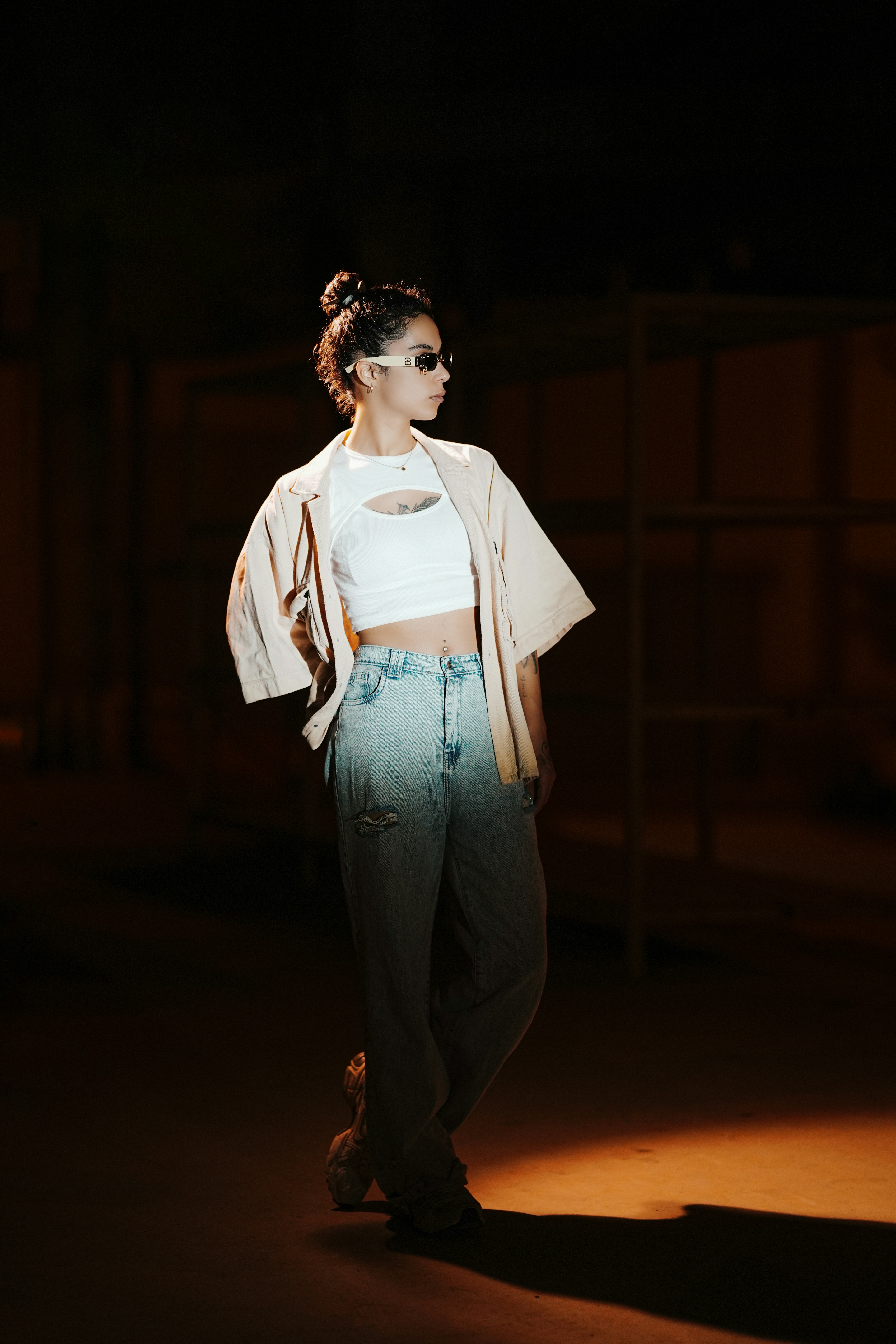 Mujer con un atuendo elegante posando bajo la luz tenue