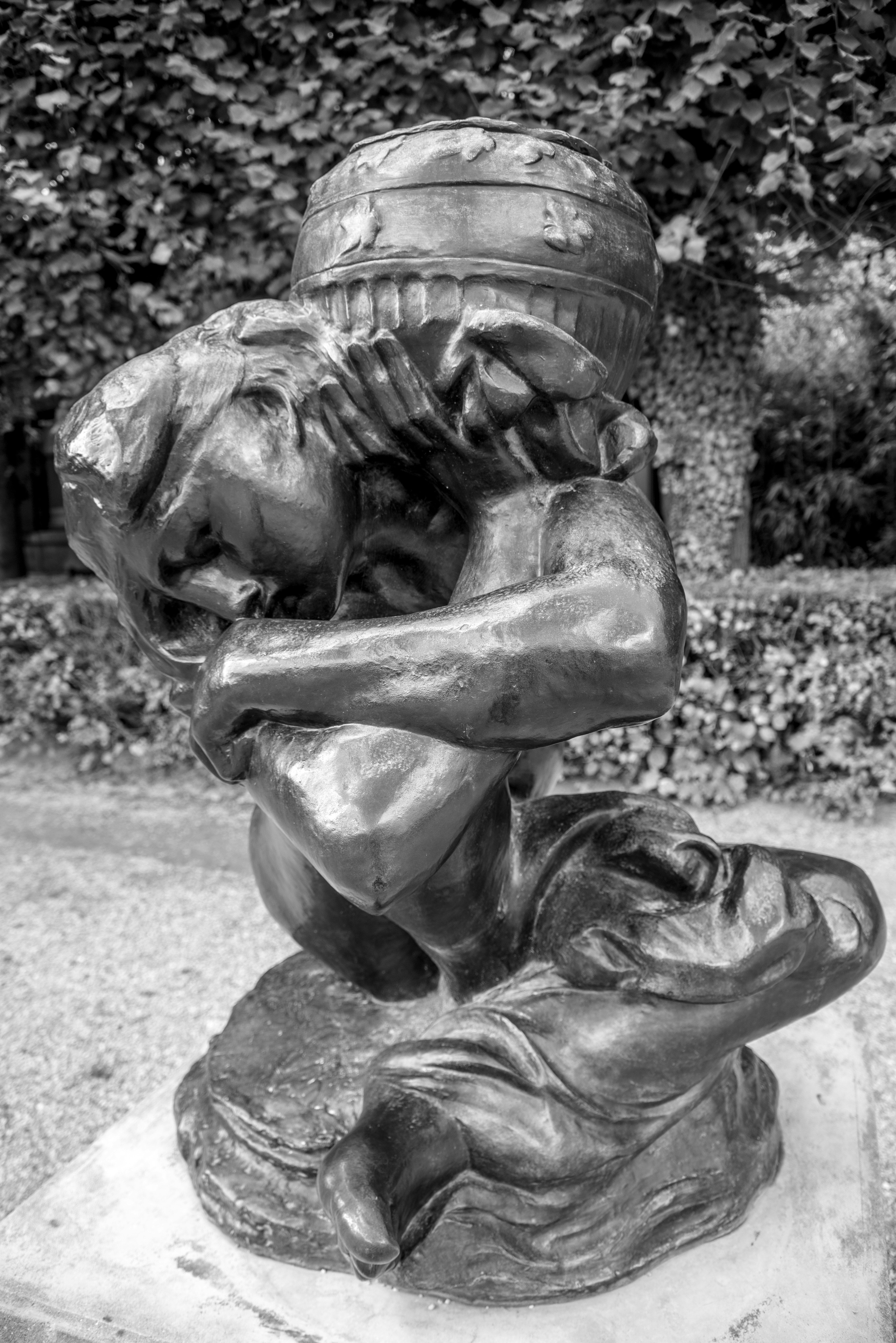 Bronze sculpture of a person carrying a large barrel.