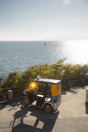 Auto rickshaw parked by the ocean on a sunny day