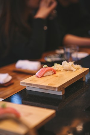 Tuna nigiri sushi with ginger and wasabi on a wooden plate, the kind of fatty tuna course sushi fans remember from Las Vegas omakase counters