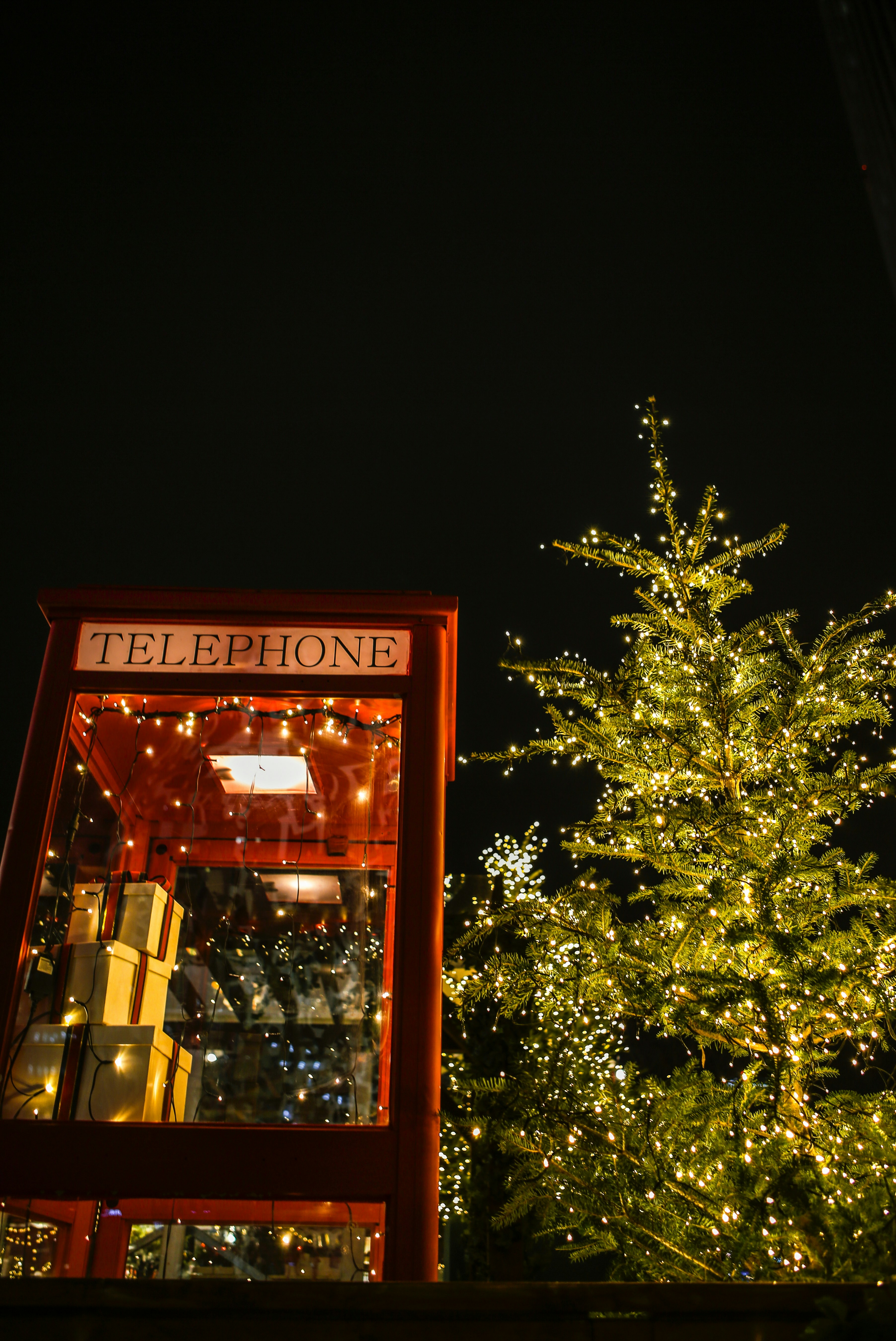 Red telephone booth decorated with christmas lights