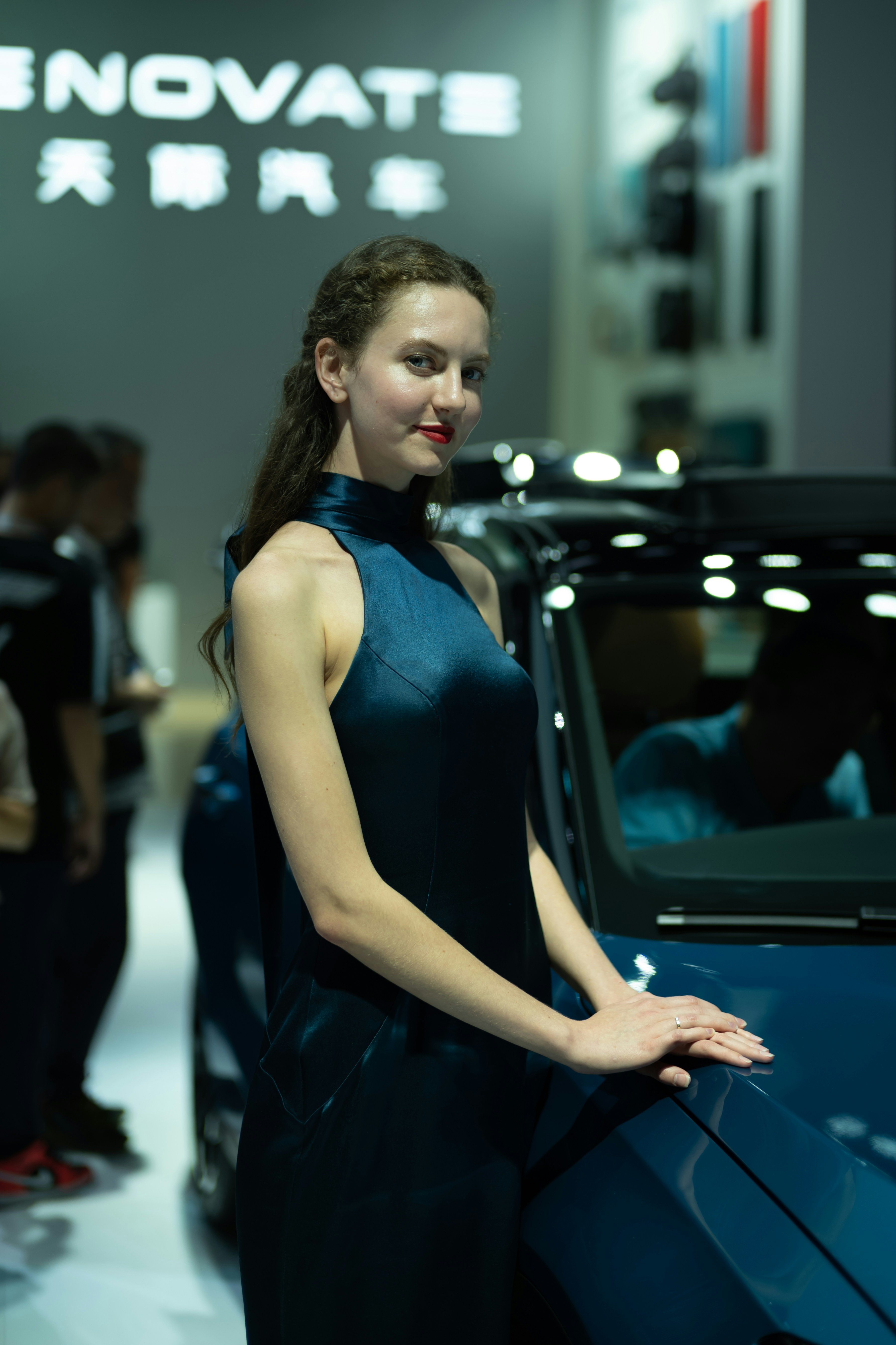 Woman in blue dress posing by car