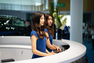 Two women in blue dresses at a reception desk.