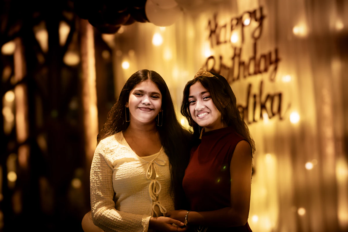 Dos invitadas sonriendo frente a luces de cumpleaños