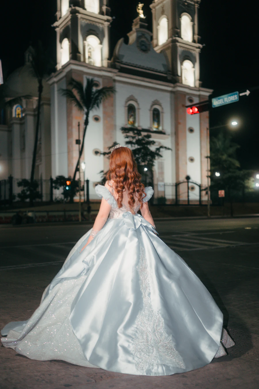 Quinceañera de espaldas frente a una iglesia iluminada