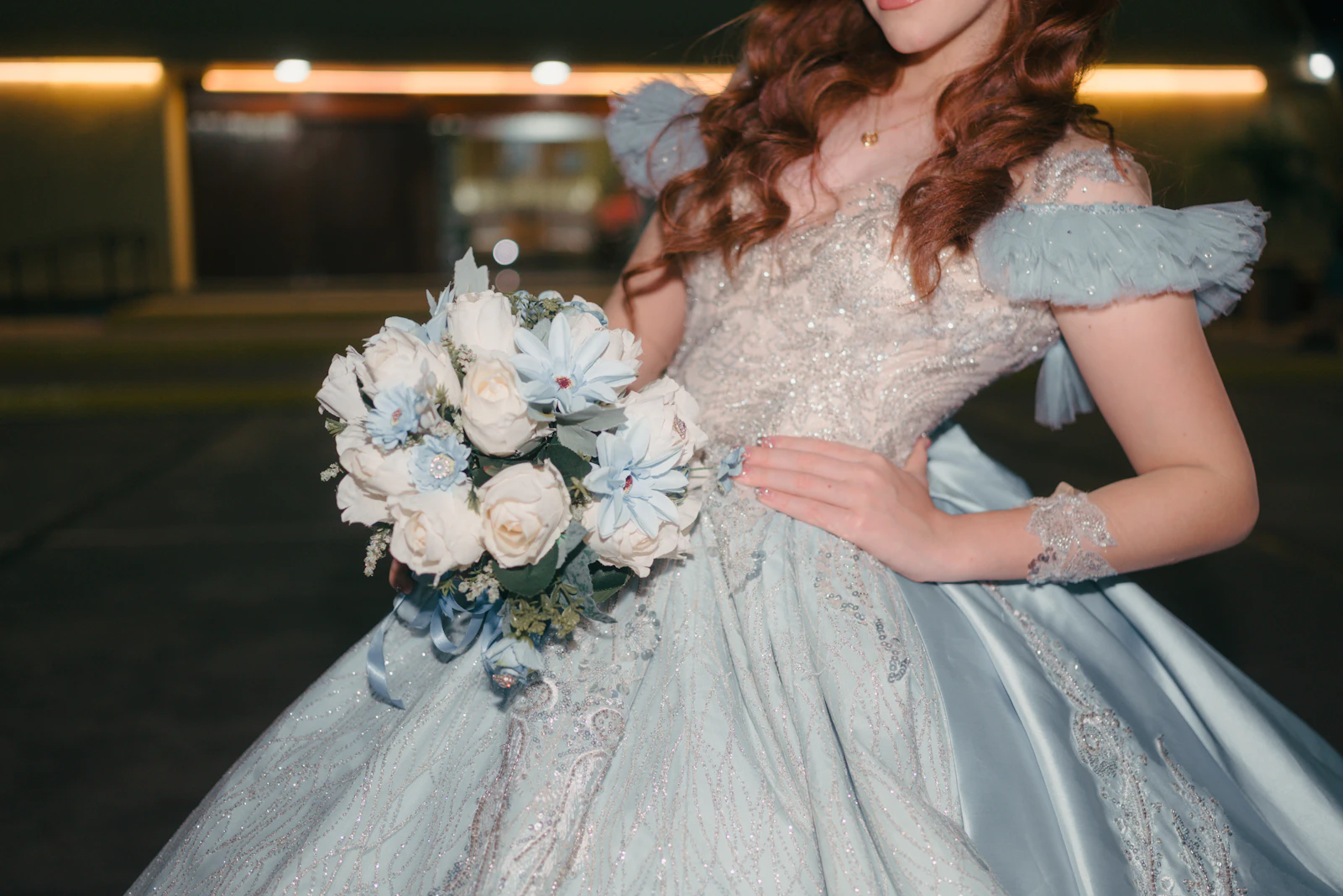 Quinceañera in a light blue ball gown holding a bouquet