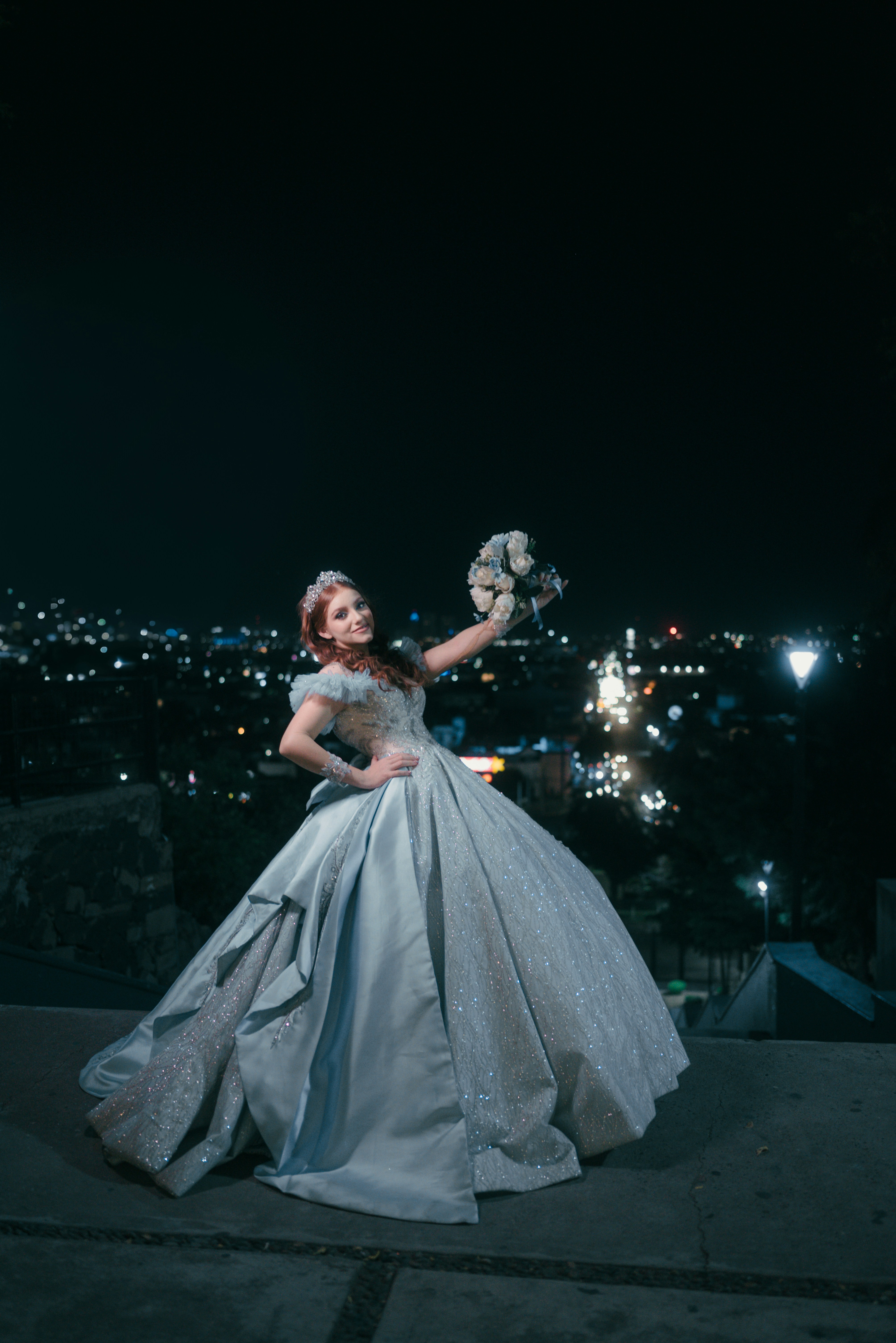 Woman in elegant gown holding bouquet at night
