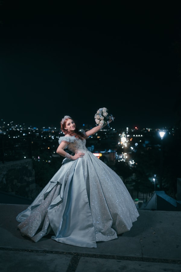 Regina Sofía de pie sobre una terraza con la ciudad iluminada de fondo, alzando su ramo