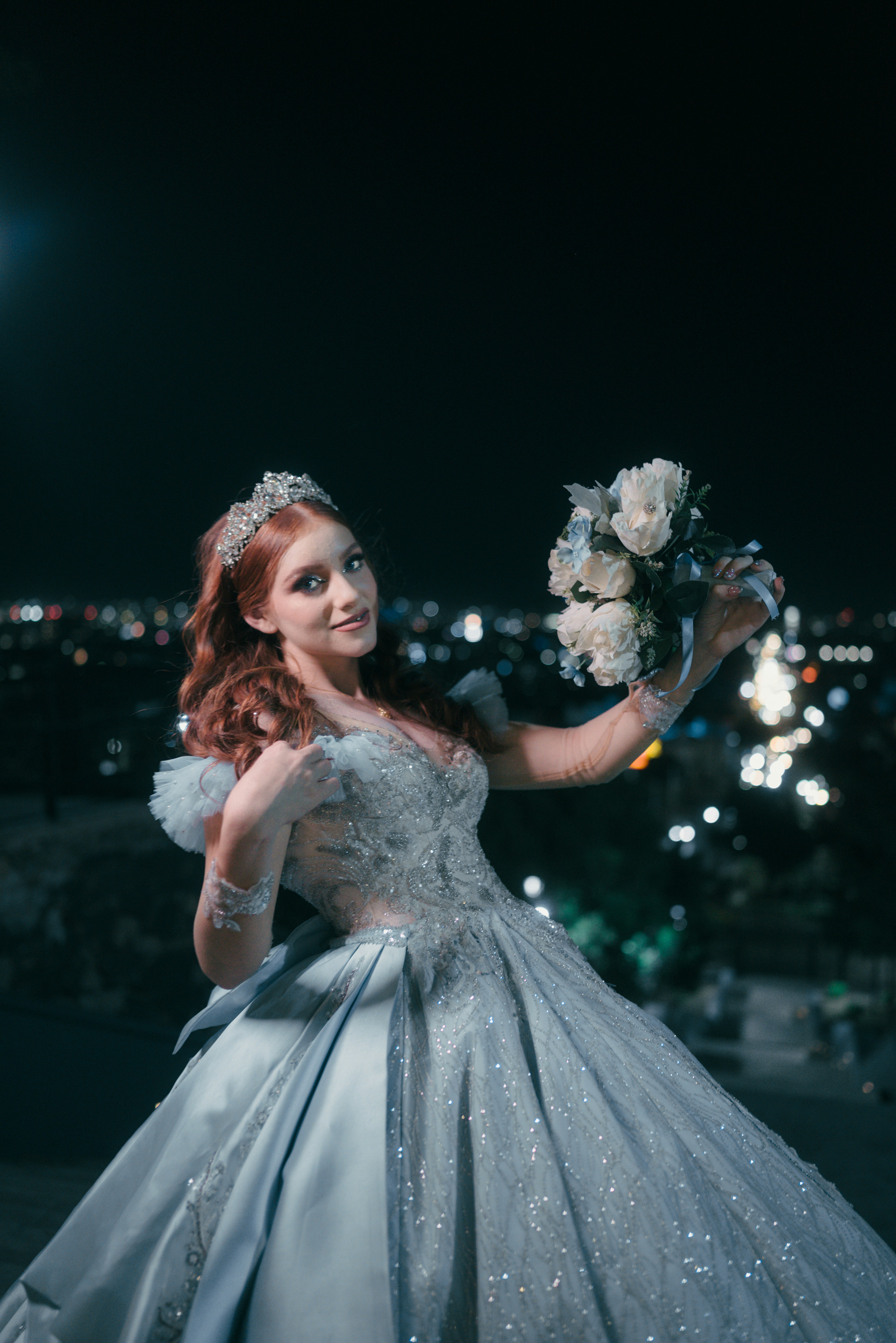 Young woman in a light blue ball gown holding flowers